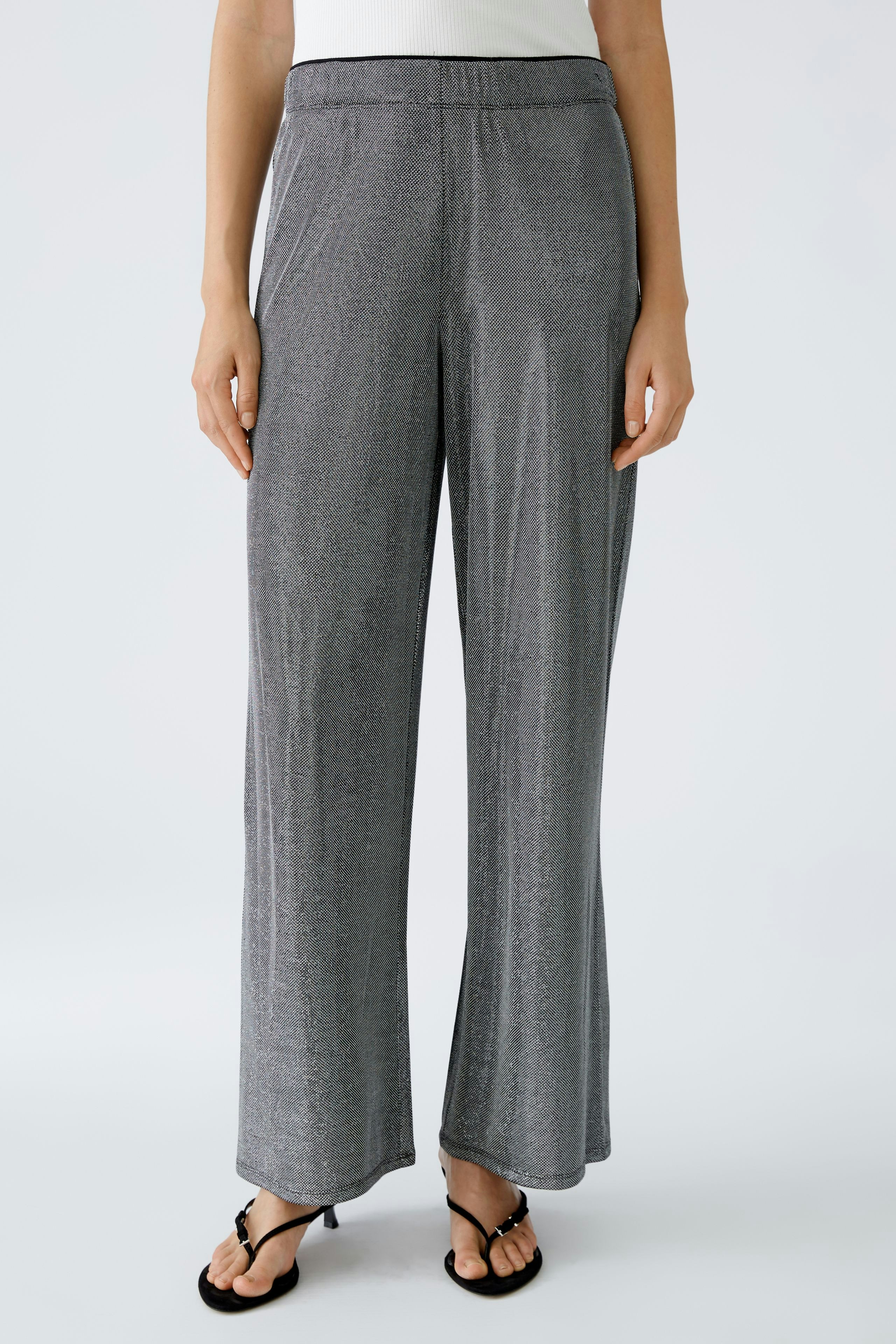 Stylish women's pants: A woman in shiny gray wide-leg pants stands confidently.