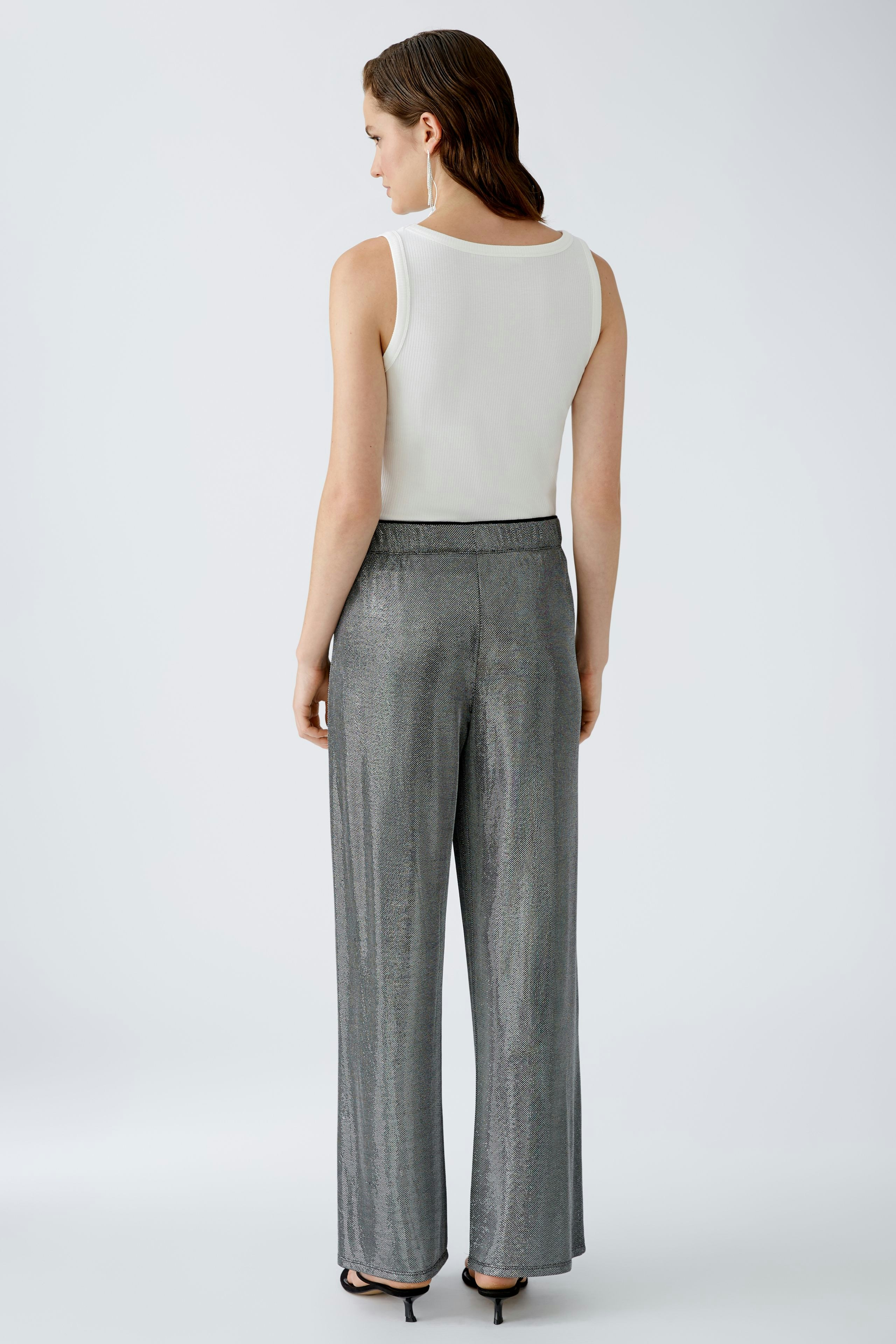 Stylish women's trousers: A woman in shimmering silver wide-leg pants, showcasing modern elegance.