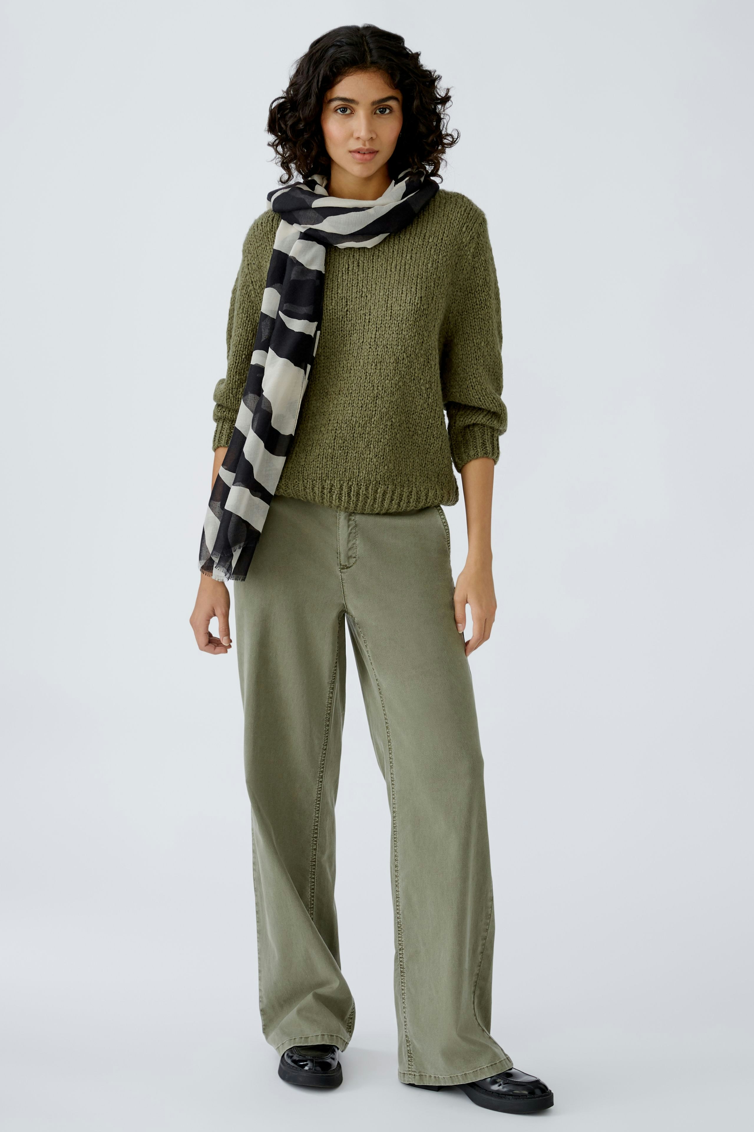 Eleganter Damen-Schal: Frau trägt einen gestreiften Schal in Schwarz und Weiß, kombiniert mit lässiger Kleidung.