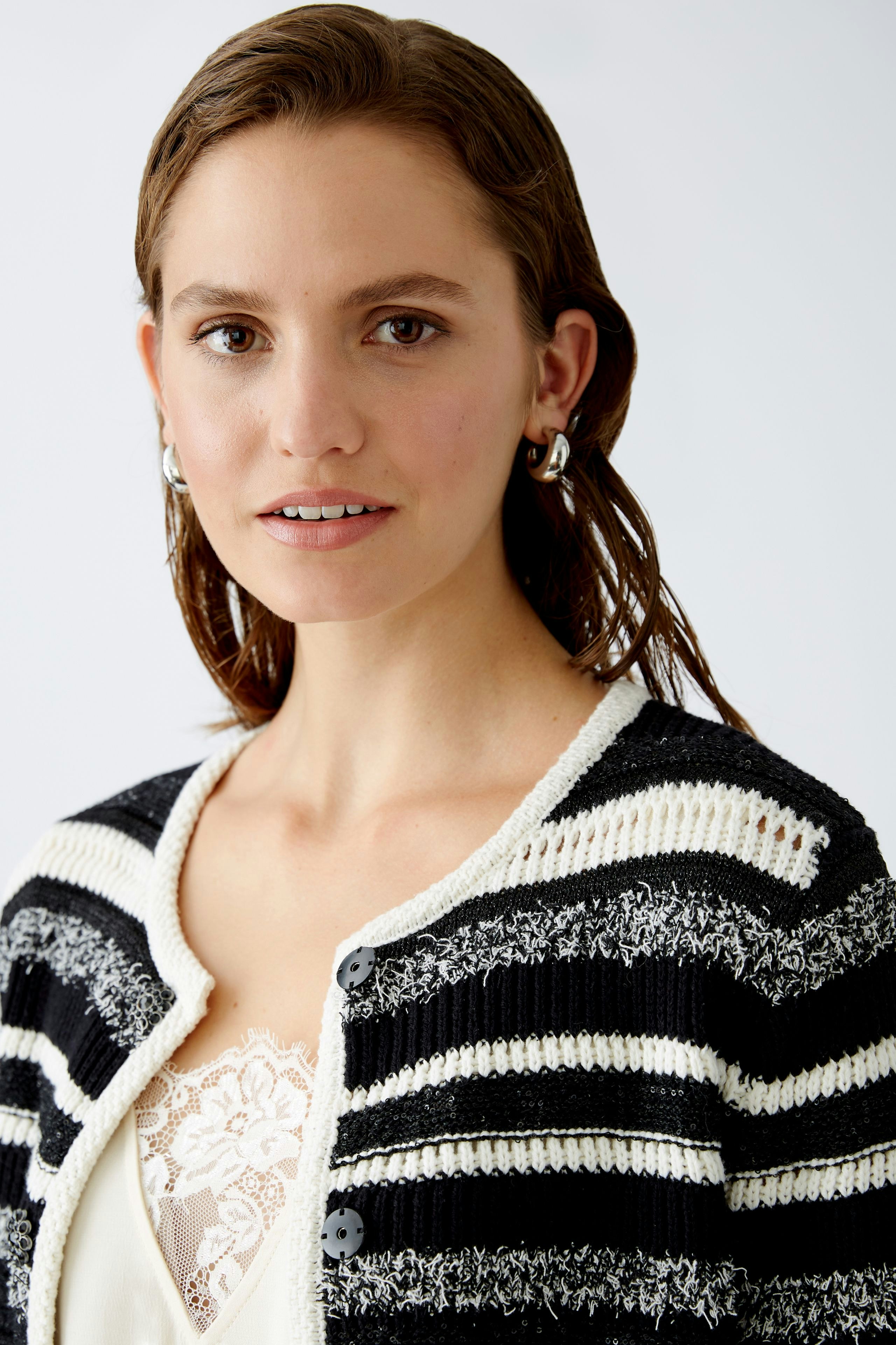 Damen-Strickjacke: Frau mit gestreifter Strickjacke in Schwarz und Weiß, lässig und stilvoll.