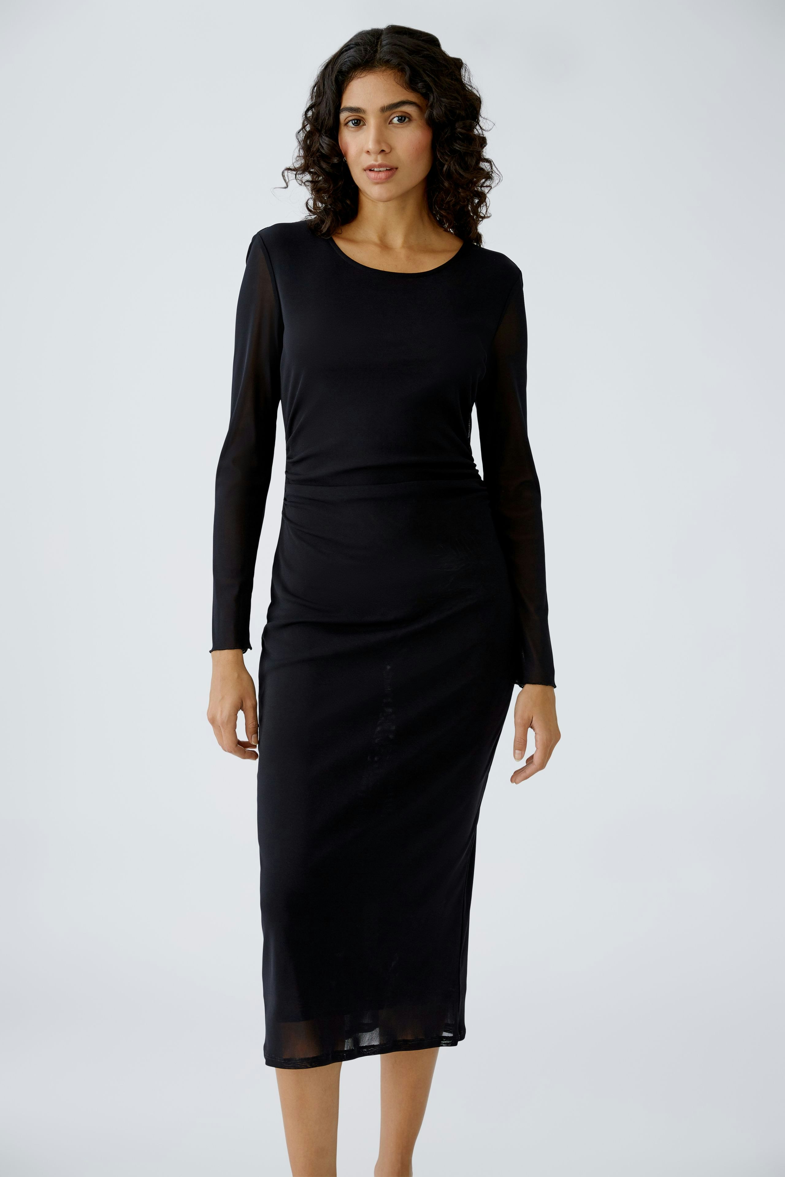 Elegant midi dress: A woman in a sleek black long-sleeve dress, showcasing a modern silhouette.