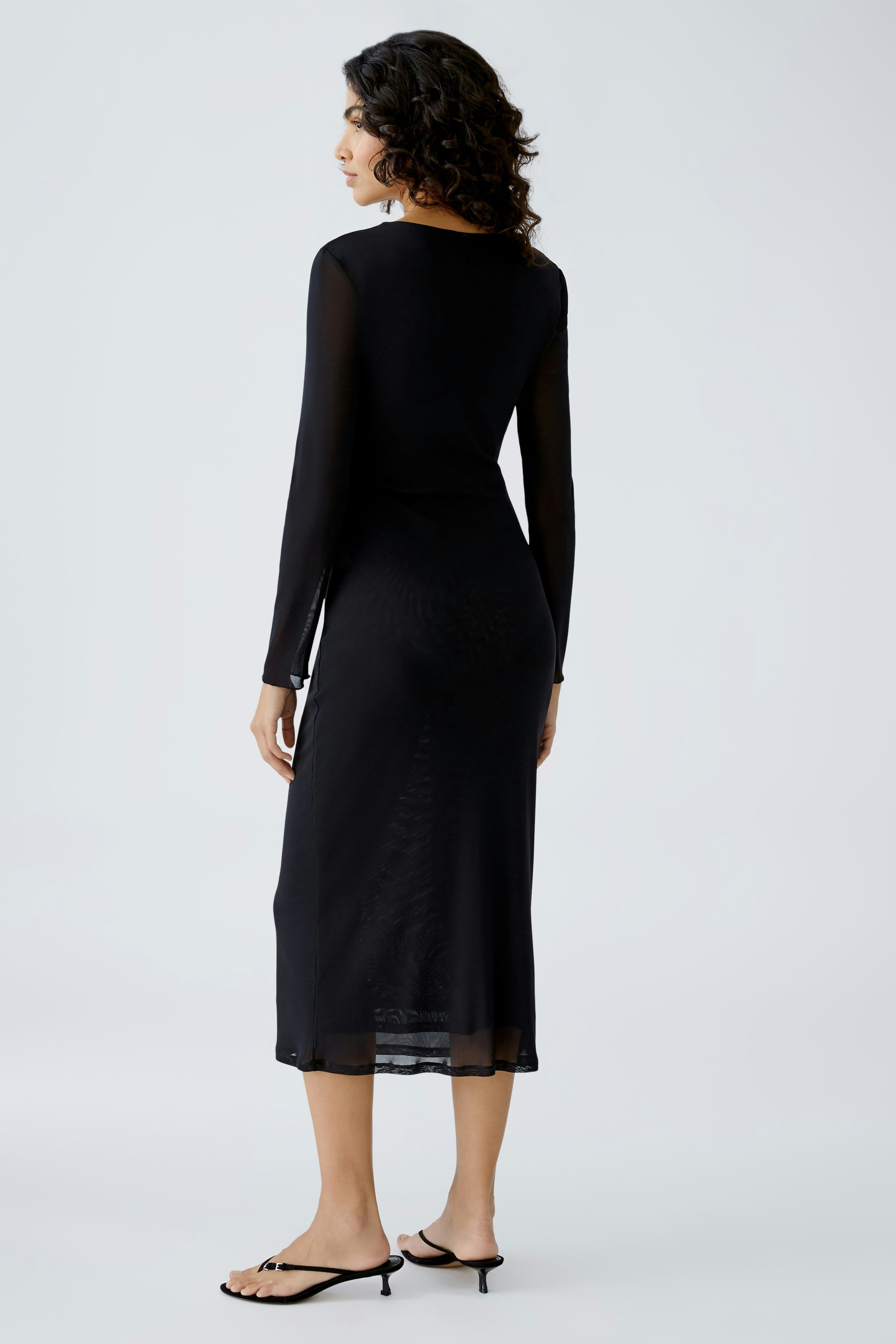 Elegant black midi dress: A woman showcases a sleek design with long sleeves and a flowing silhouette.