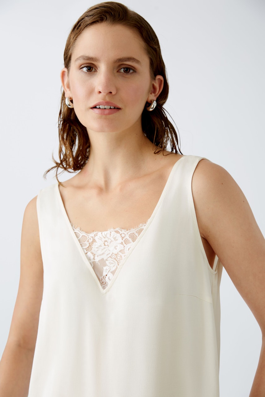 Elegant women's top with lace detail, featuring a V-neckline and a relaxed fit.