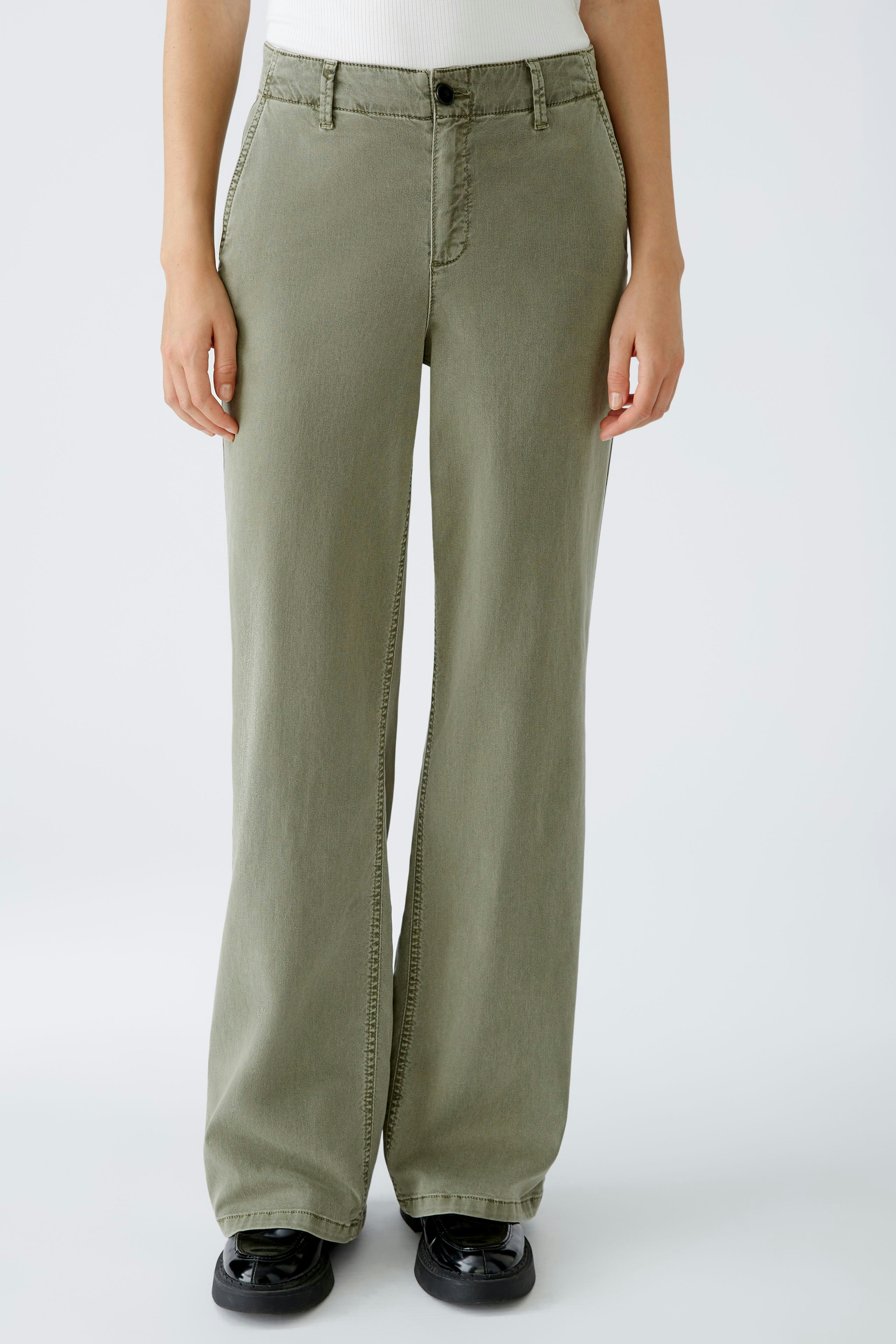 Stylish women's trousers: A woman in olive green wide-leg pants stands confidently.