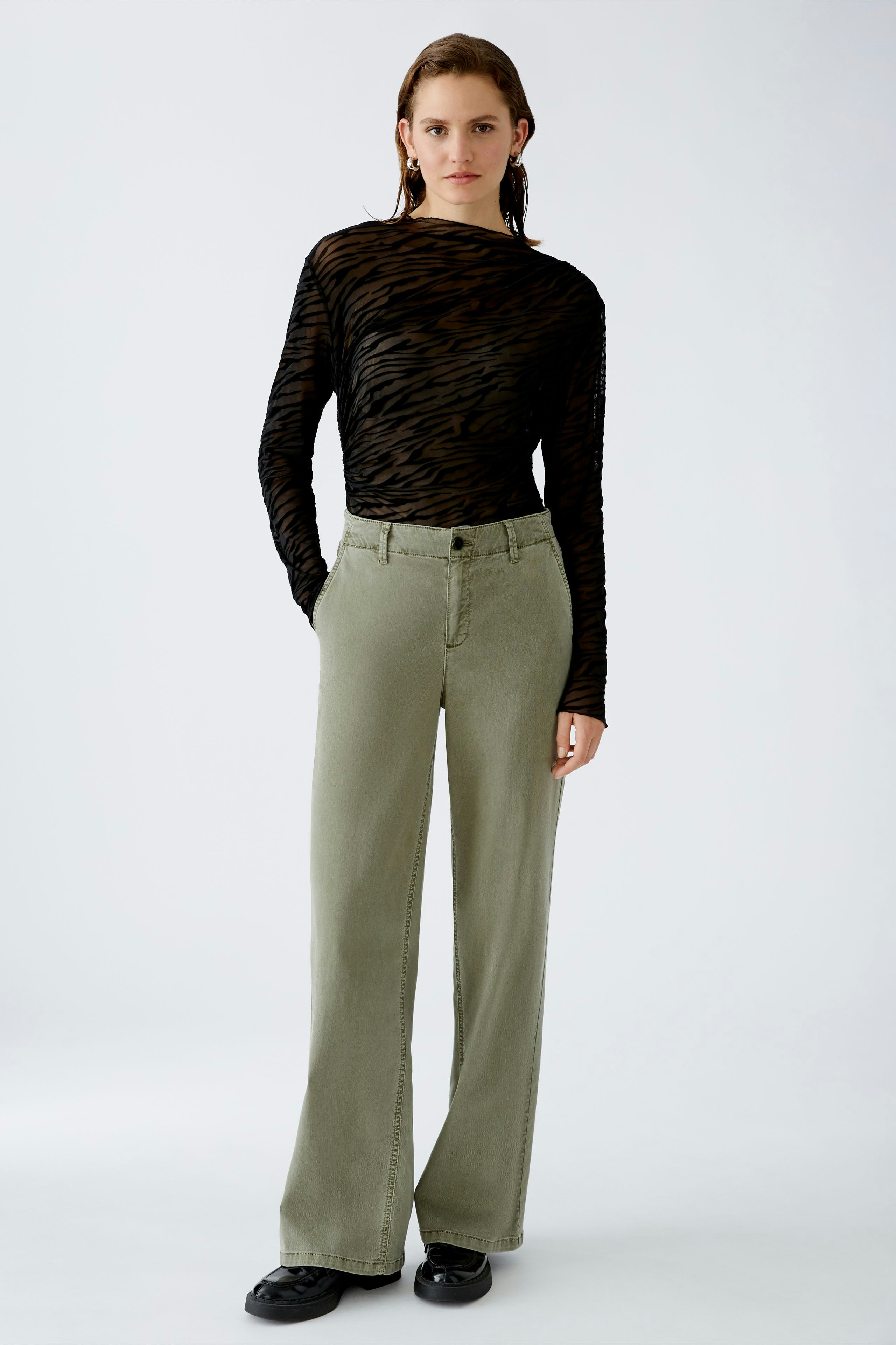 Stylish women's trousers: A woman in olive green wide-leg pants stands confidently.