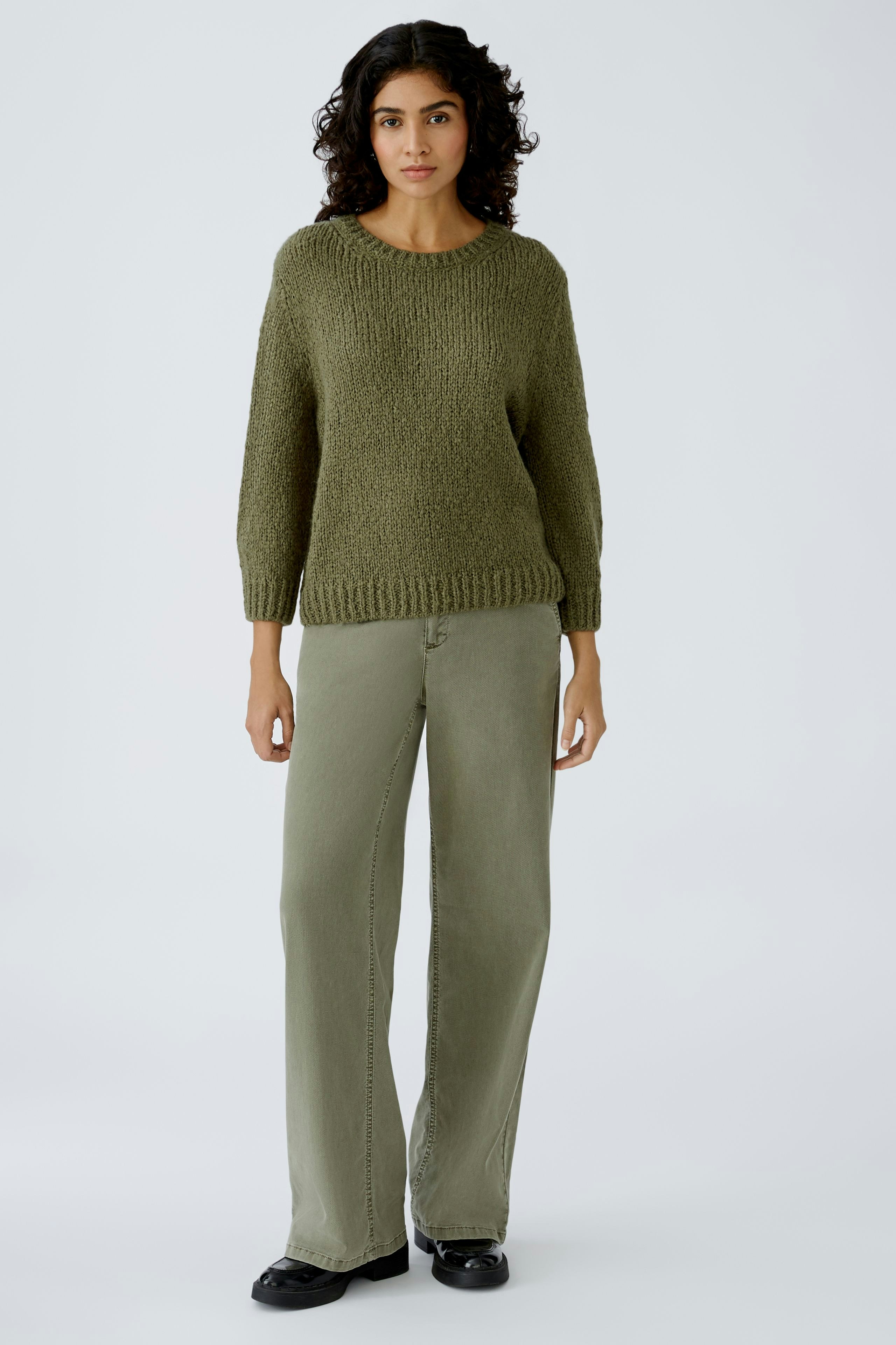 Stylish women's pullover: A woman in a cozy green knit pullover paired with relaxed-fit pants.