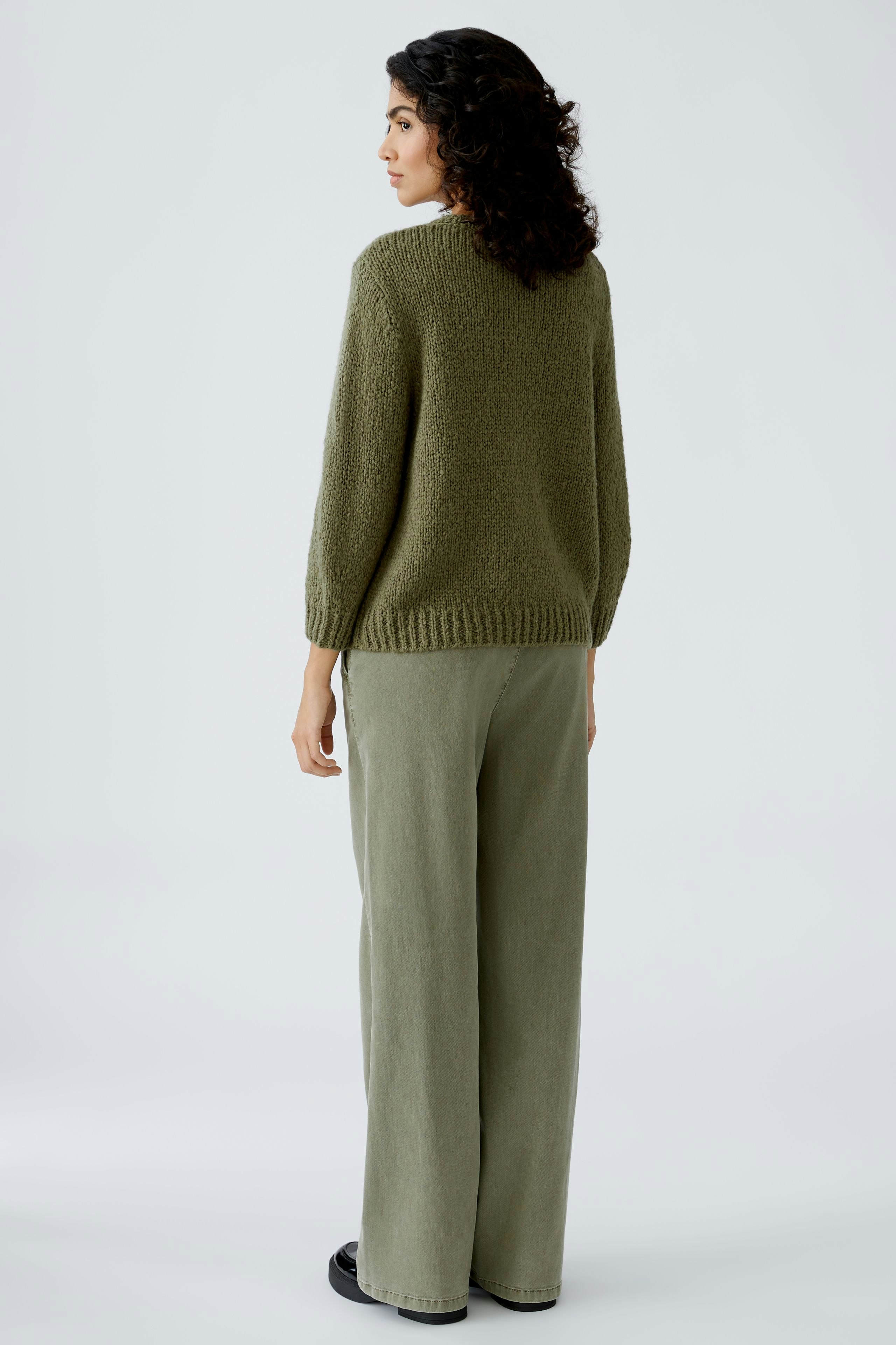 Stylish women's pullover: A woman in a cozy green pullover paired with relaxed-fit pants.