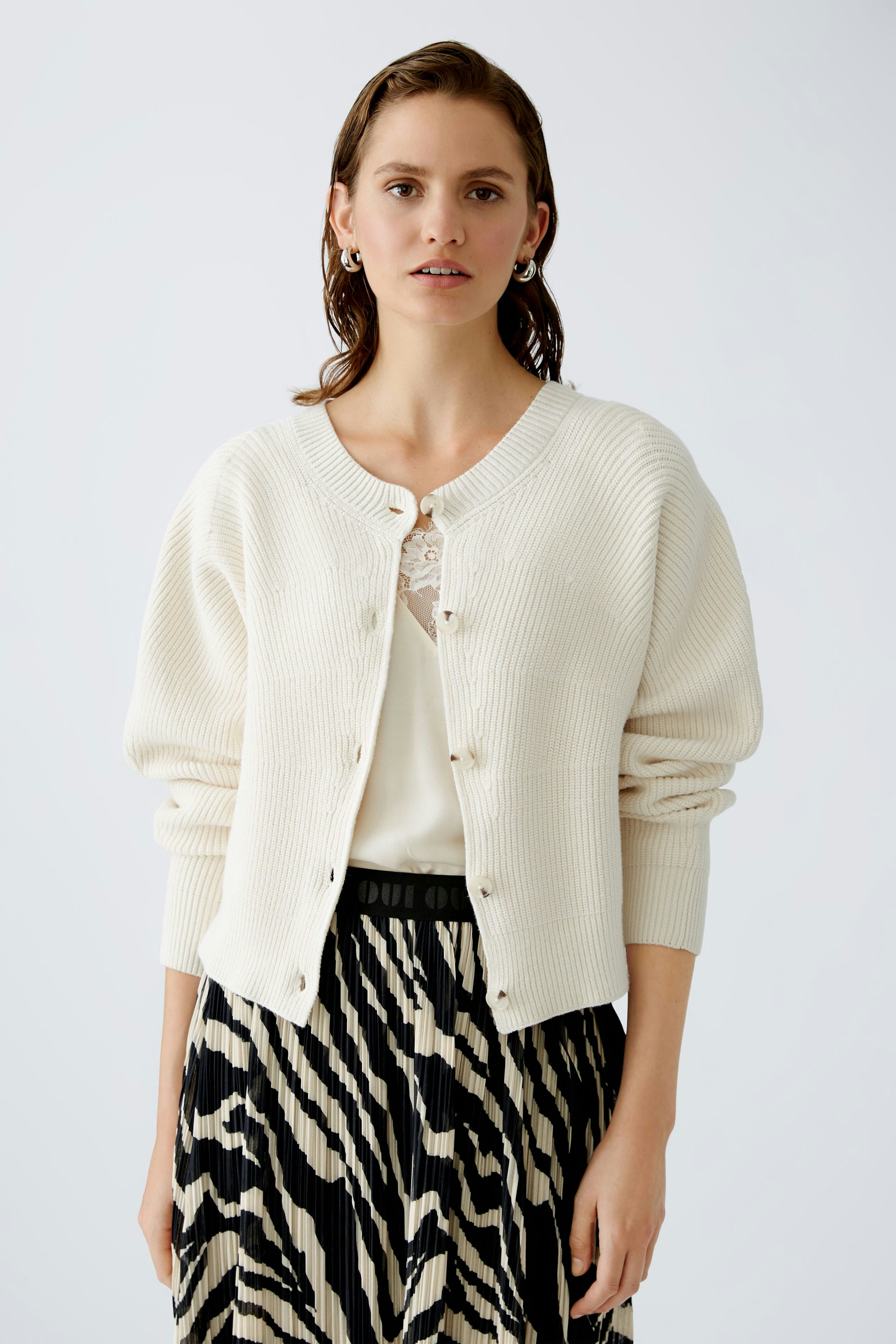 Stylish women's cardigan: A woman in a cream cardigan with buttons, paired with a chic patterned skirt.