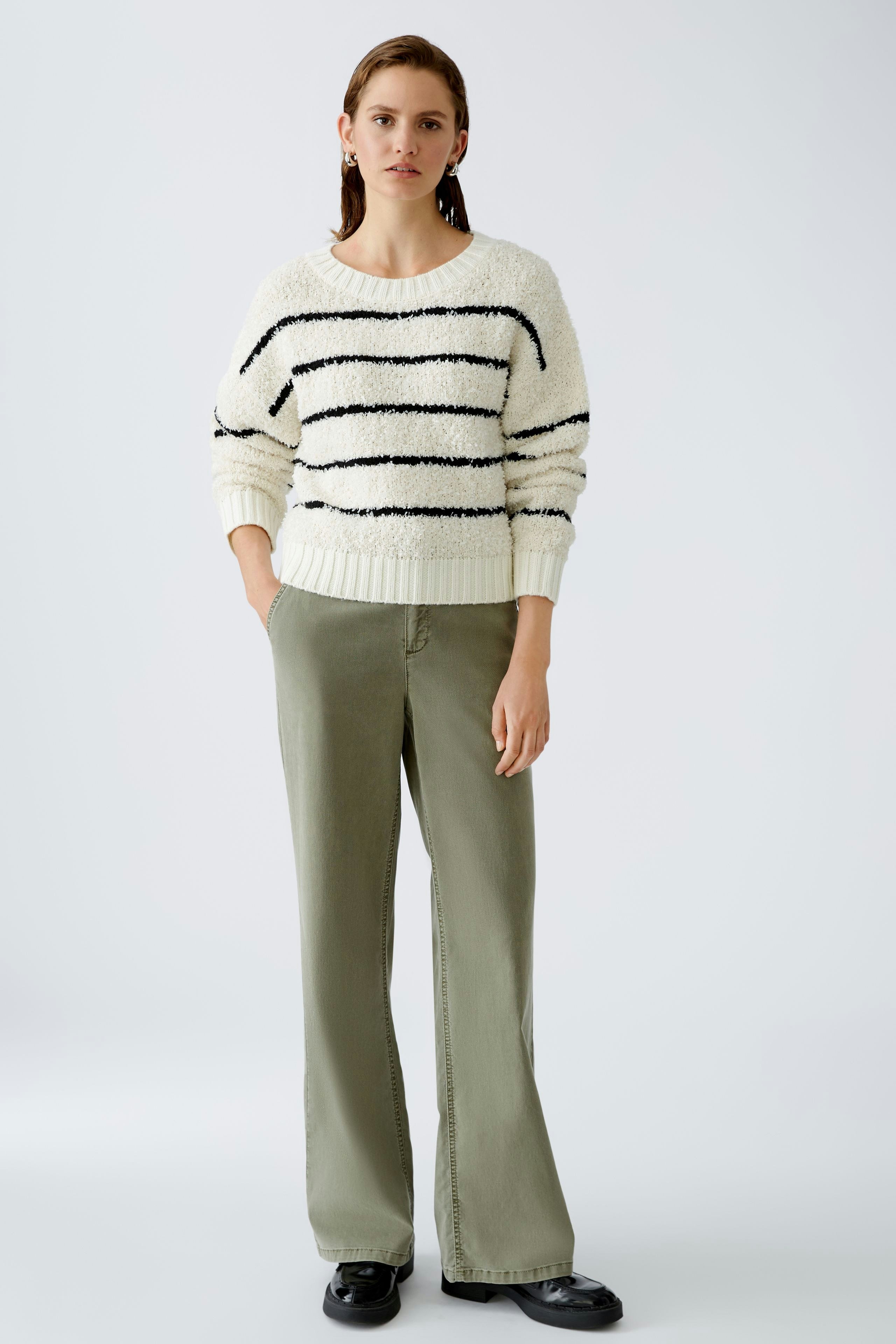 Damen-Pullover: Junge Frau im gestreiften, weißen Strickpullover mit lässigen Hosen.