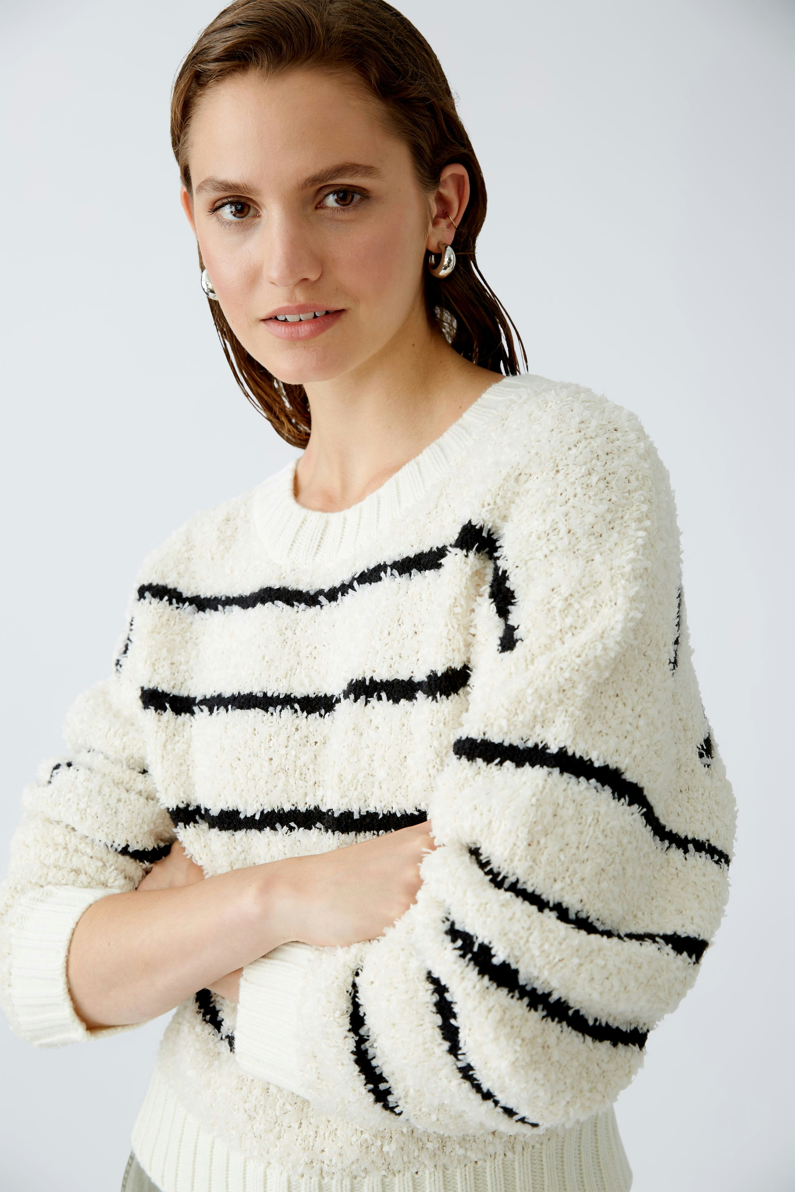 Damen-Pullover: Frau in weißem, gestreiften Strickpullover mit lässigem Schnitt und weichem Material.