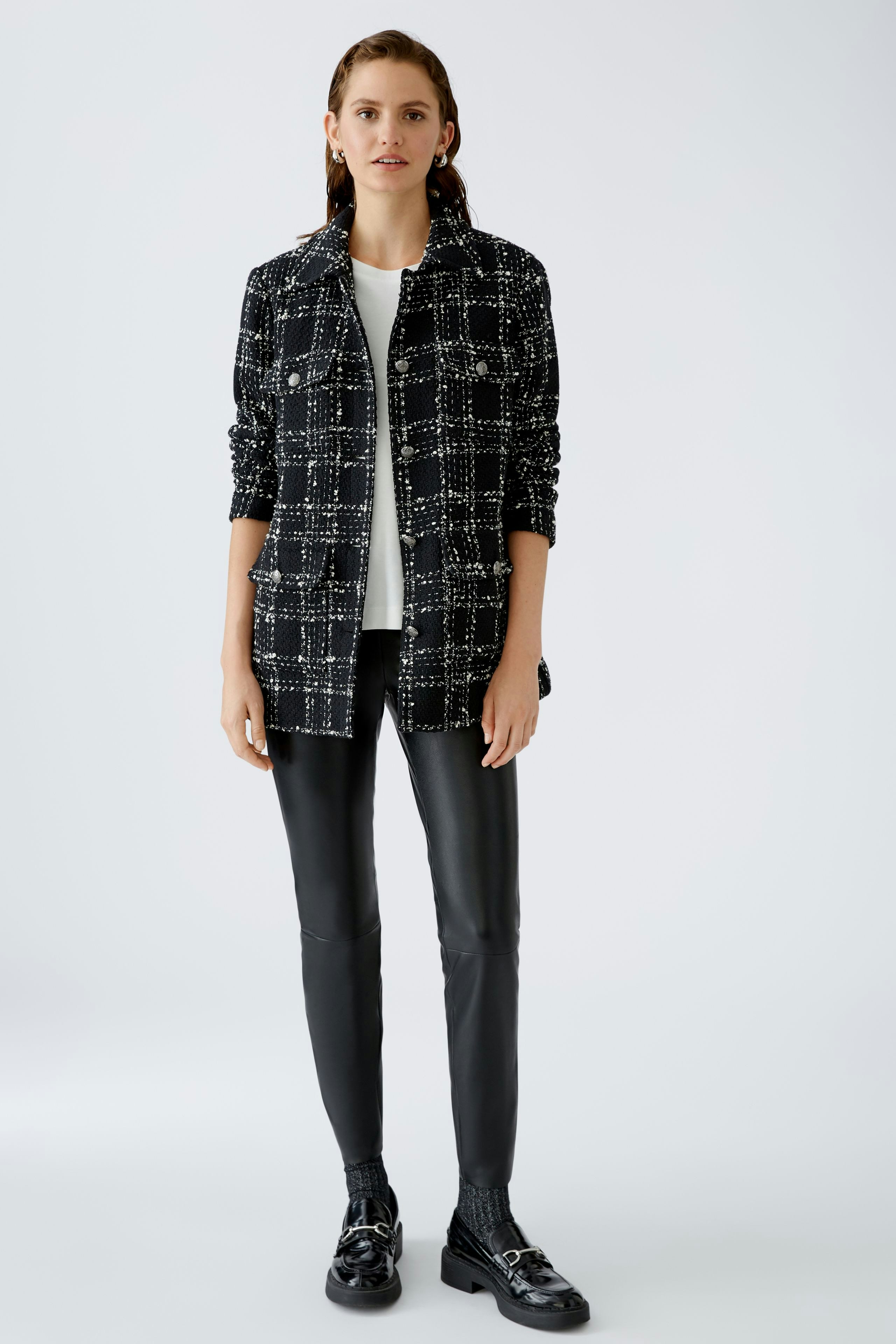 Stylish women's jacket: A woman in a black and white patterned jacket paired with sleek pants.