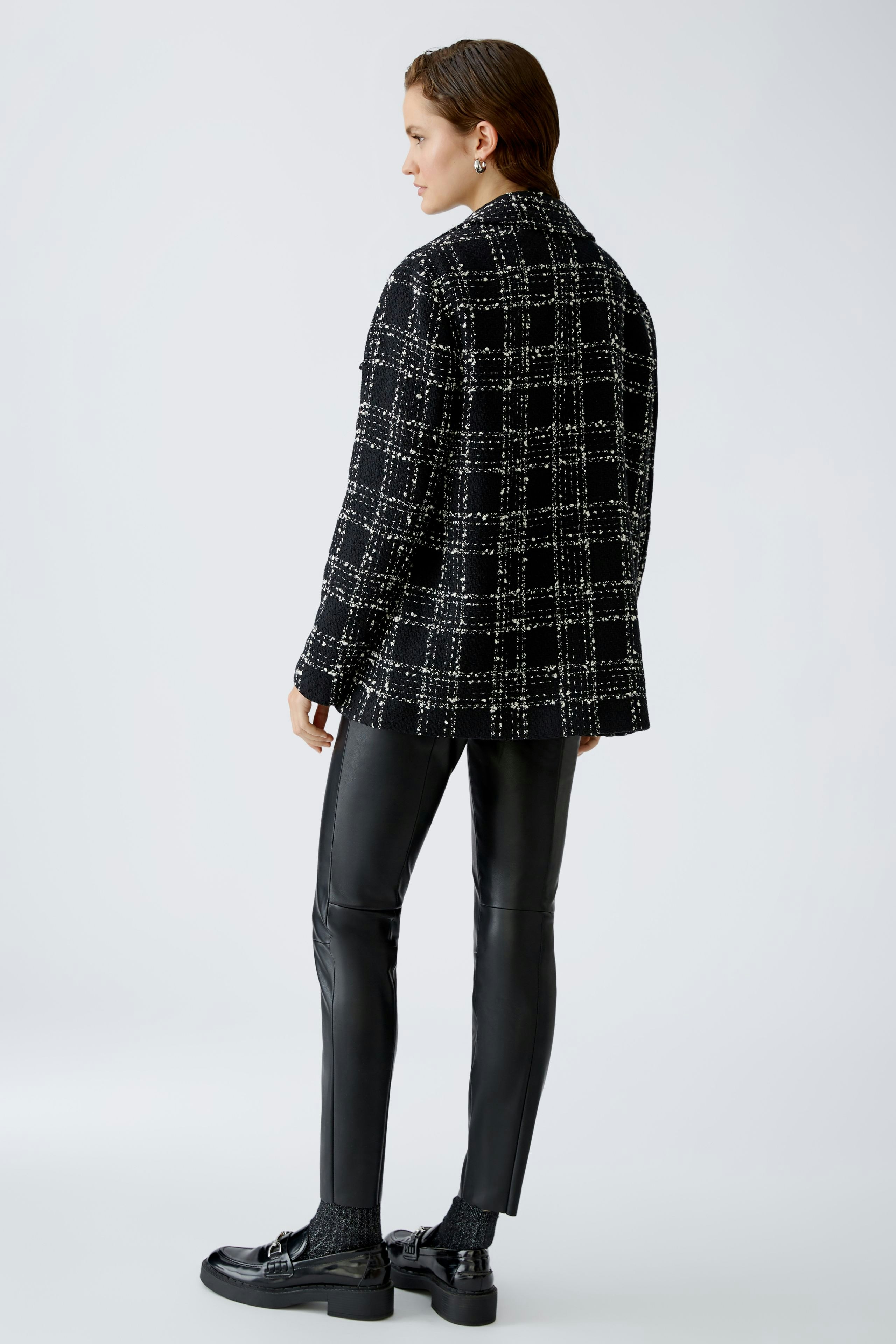 Chic women's jacket: A woman in a stylish black and white checked jacket, exuding elegance.
