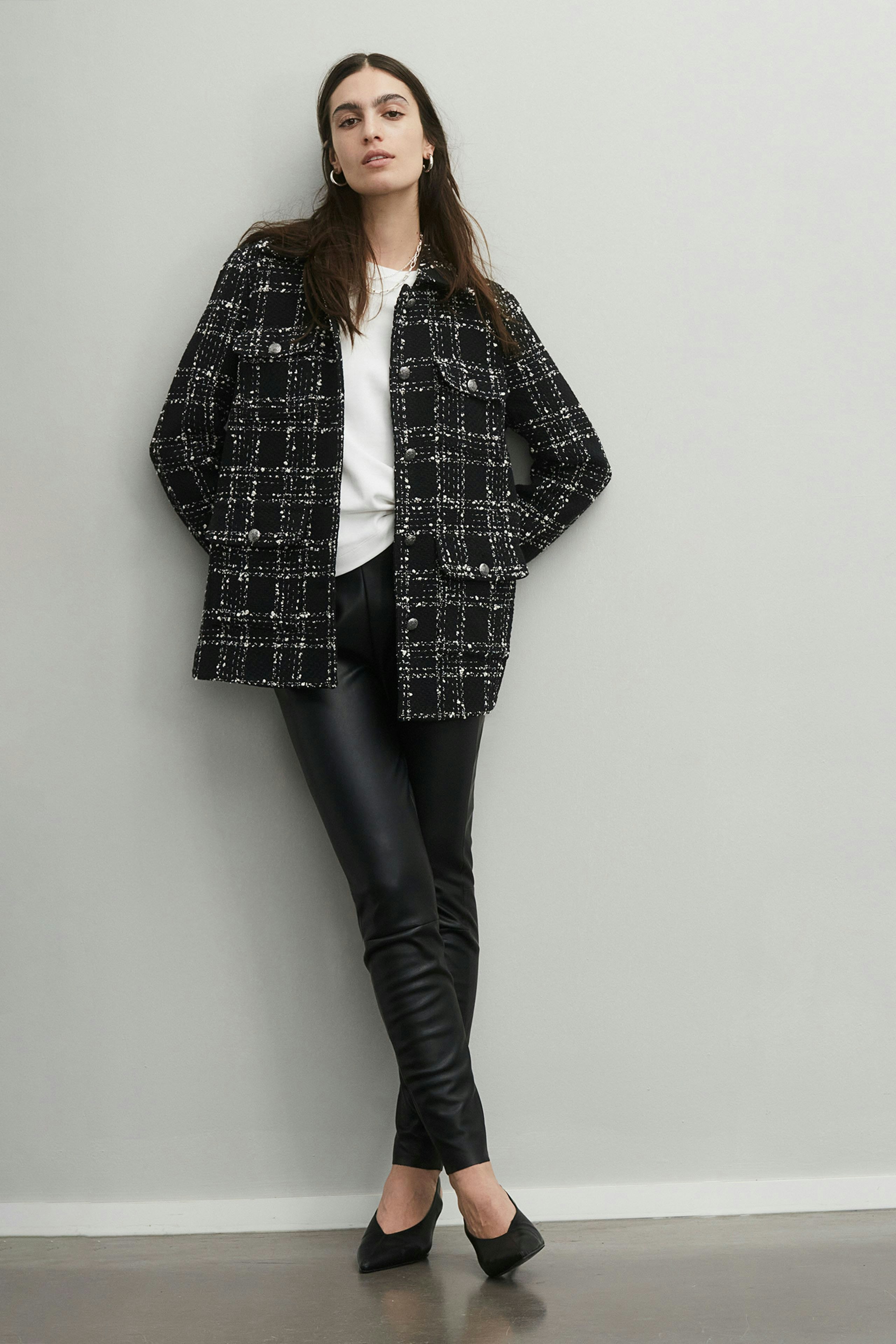 Stylish women's jacket: A woman in a black and white checkered jacket paired with sleek black pants.