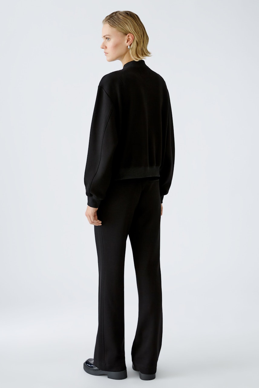 Stylish women's blouson: A woman in a black pullover and matching pants, showcasing a modern look.