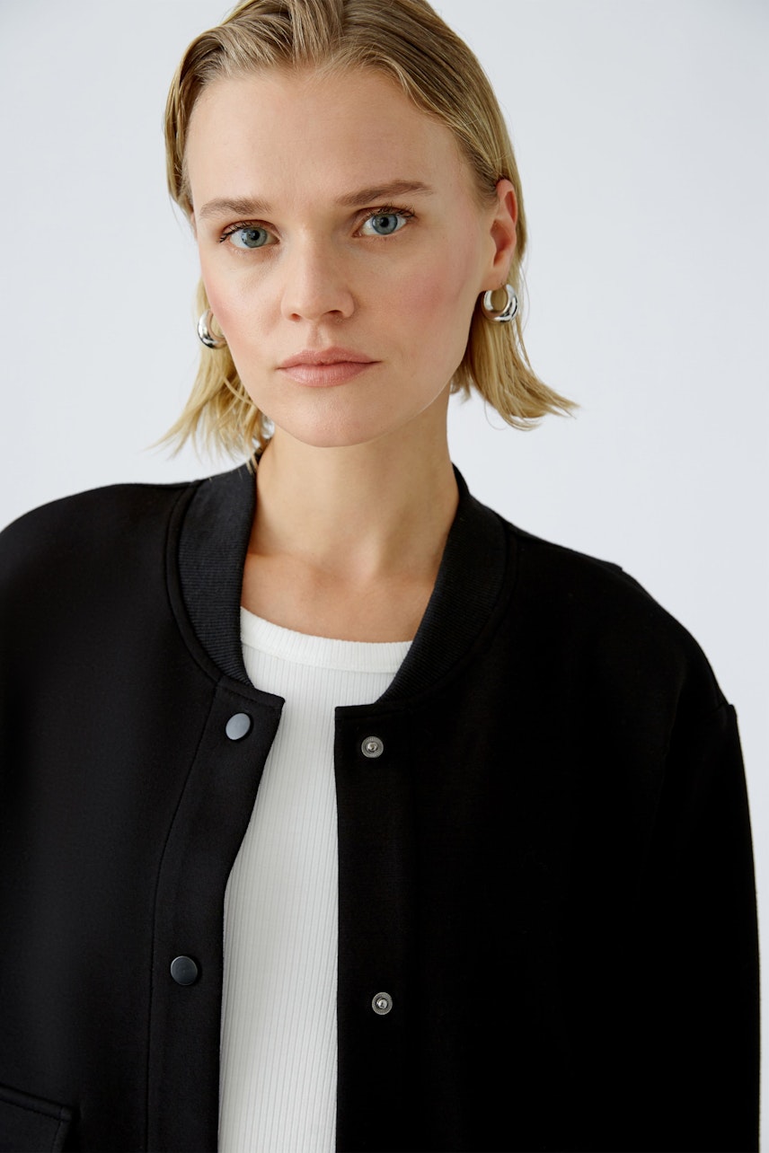 Stylish women's blouson: A woman in a black bomber jacket, exuding confidence and modern elegance.