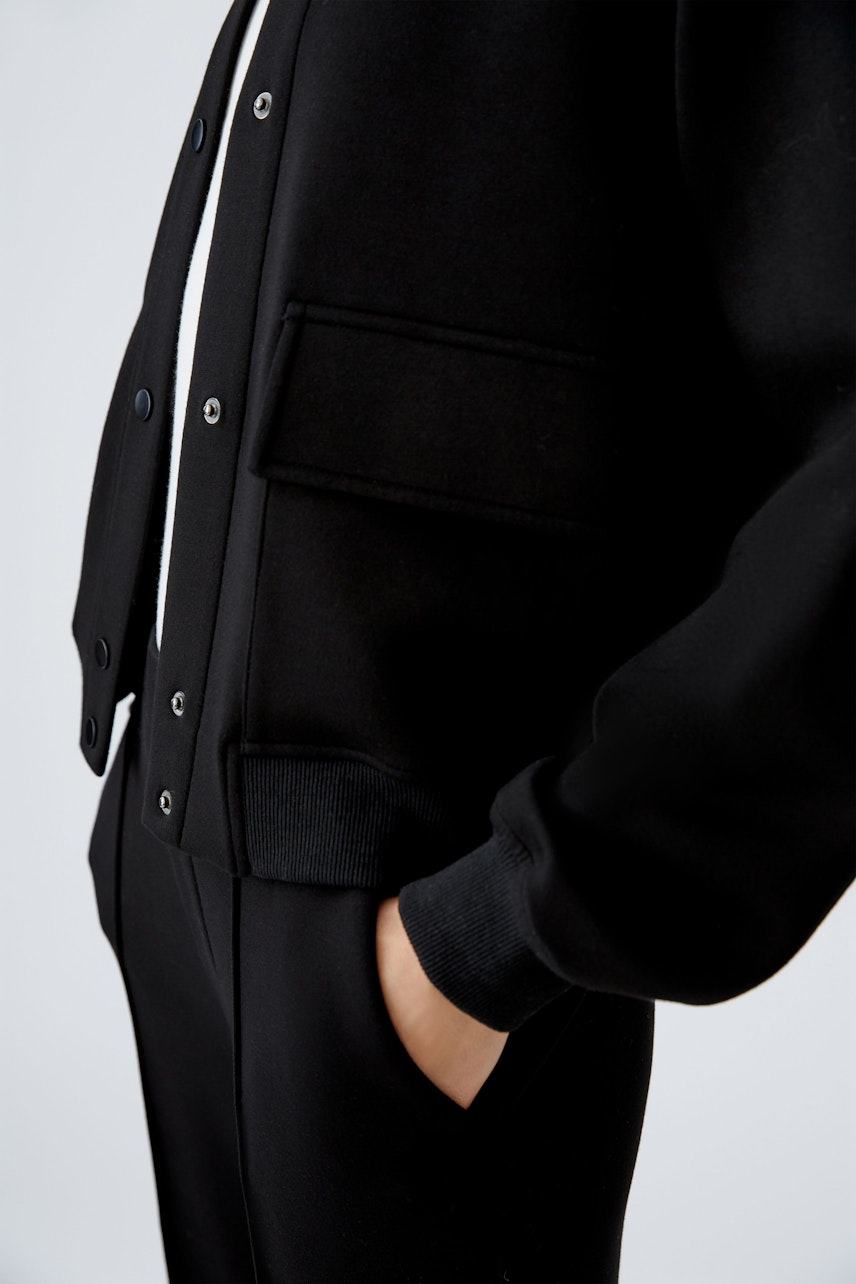 Stylish women's blouson: A close-up of a black bomber jacket with a relaxed fit and practical pockets.