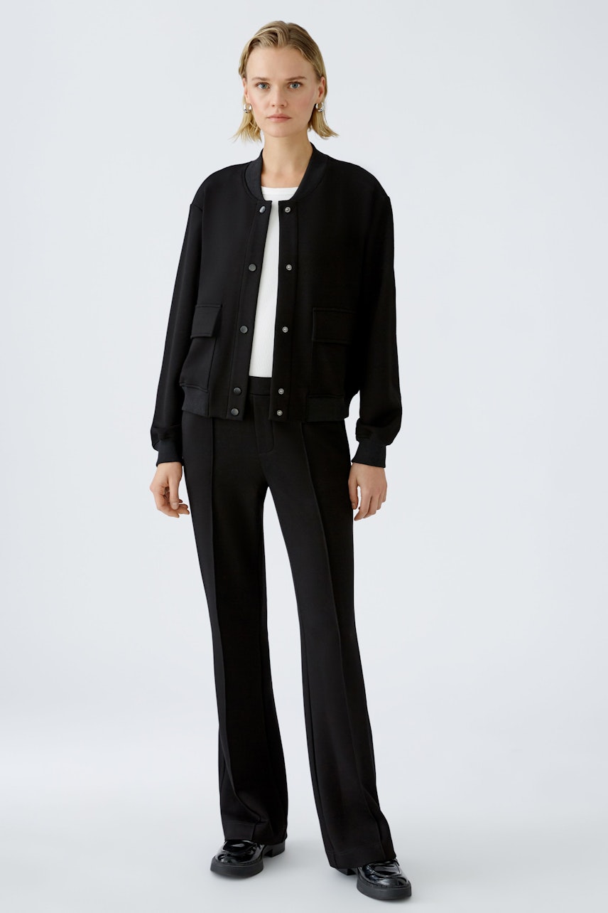 Stylish women's blouson: A woman in a black bomber jacket paired with sleek trousers.