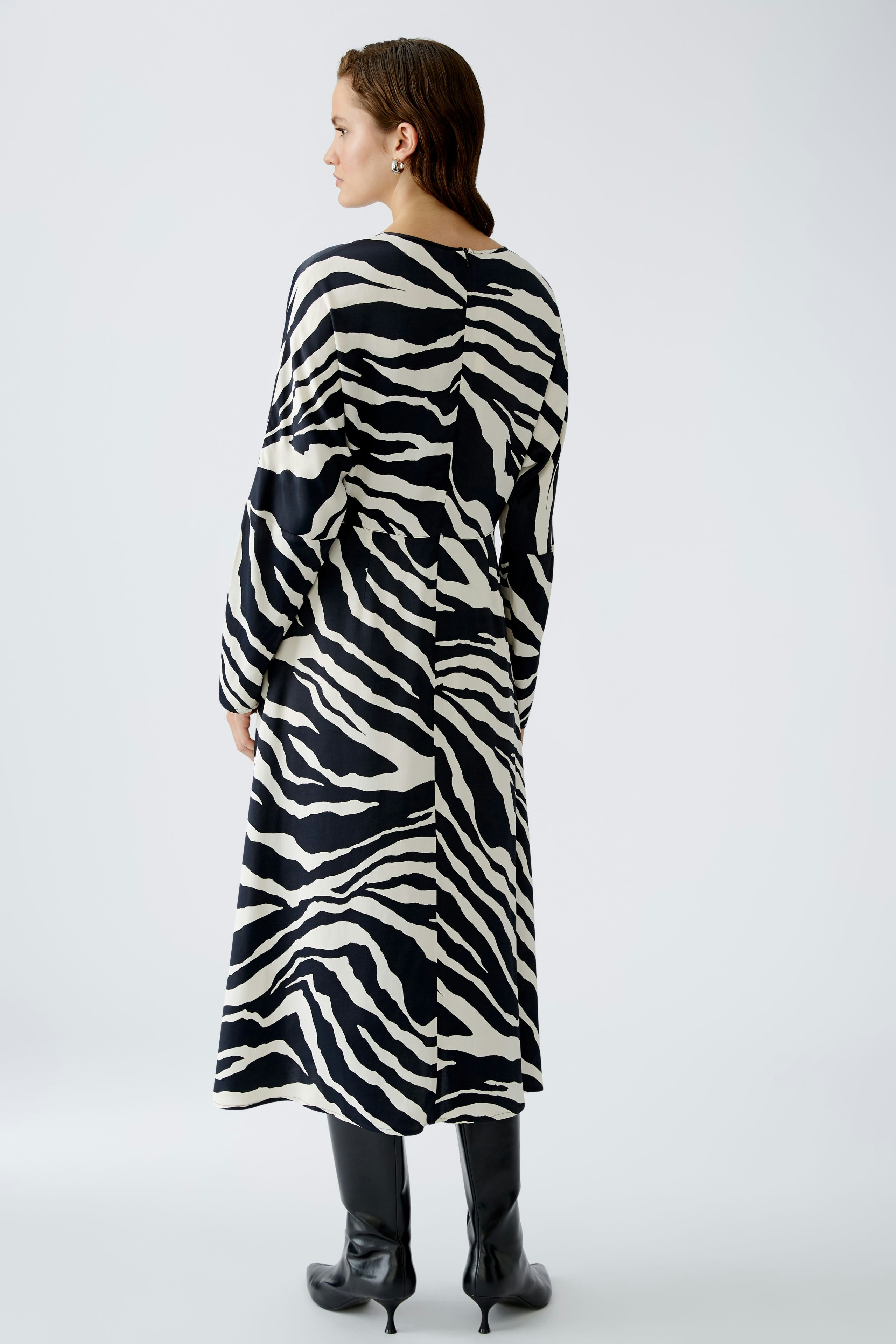 Stylish midi dress: Woman in a black and white zebra print dress, showcasing a modern and elegant look.
