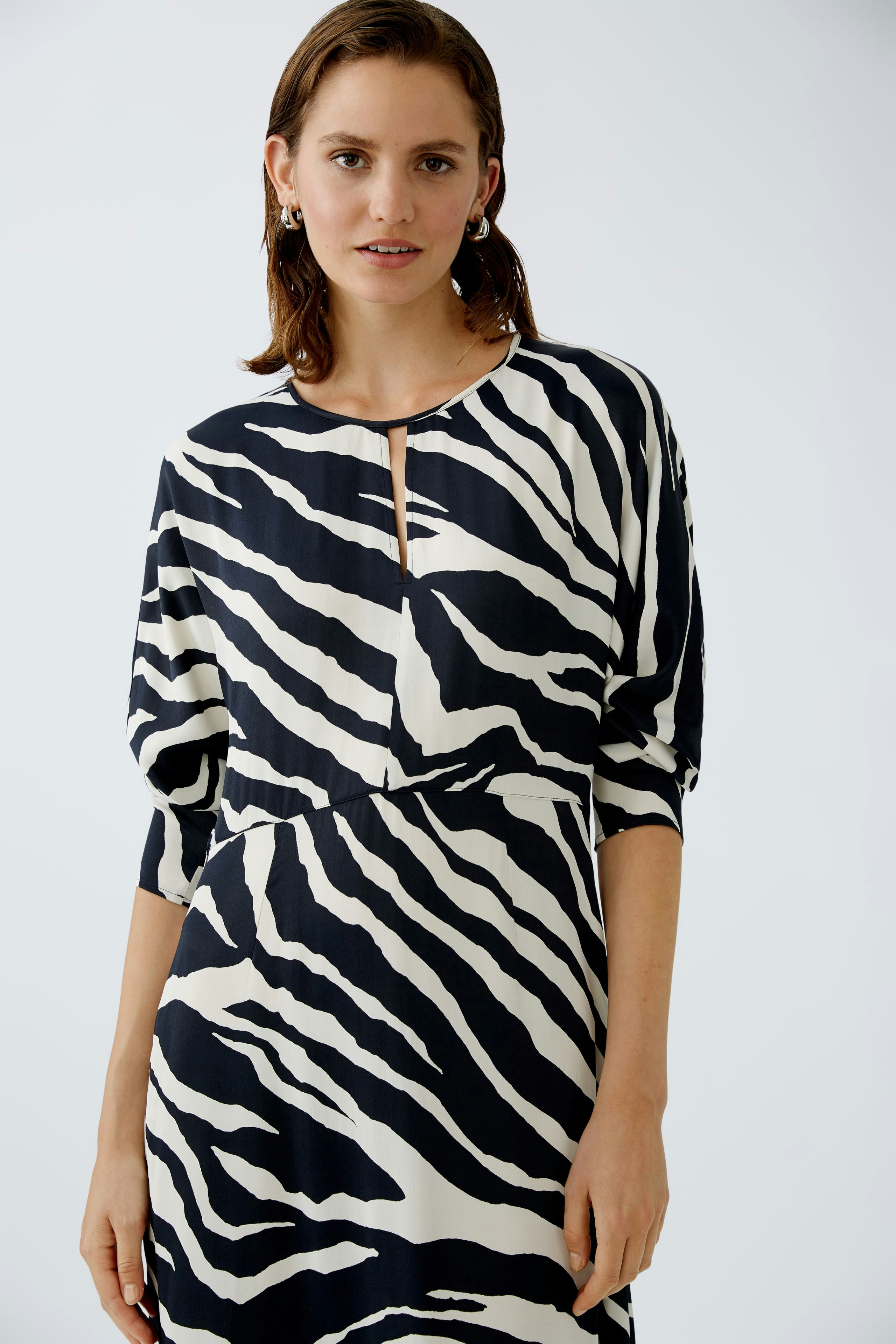 Stylish midi dress: Woman in a black and white zebra print dress with a relaxed fit and elegant neckline.