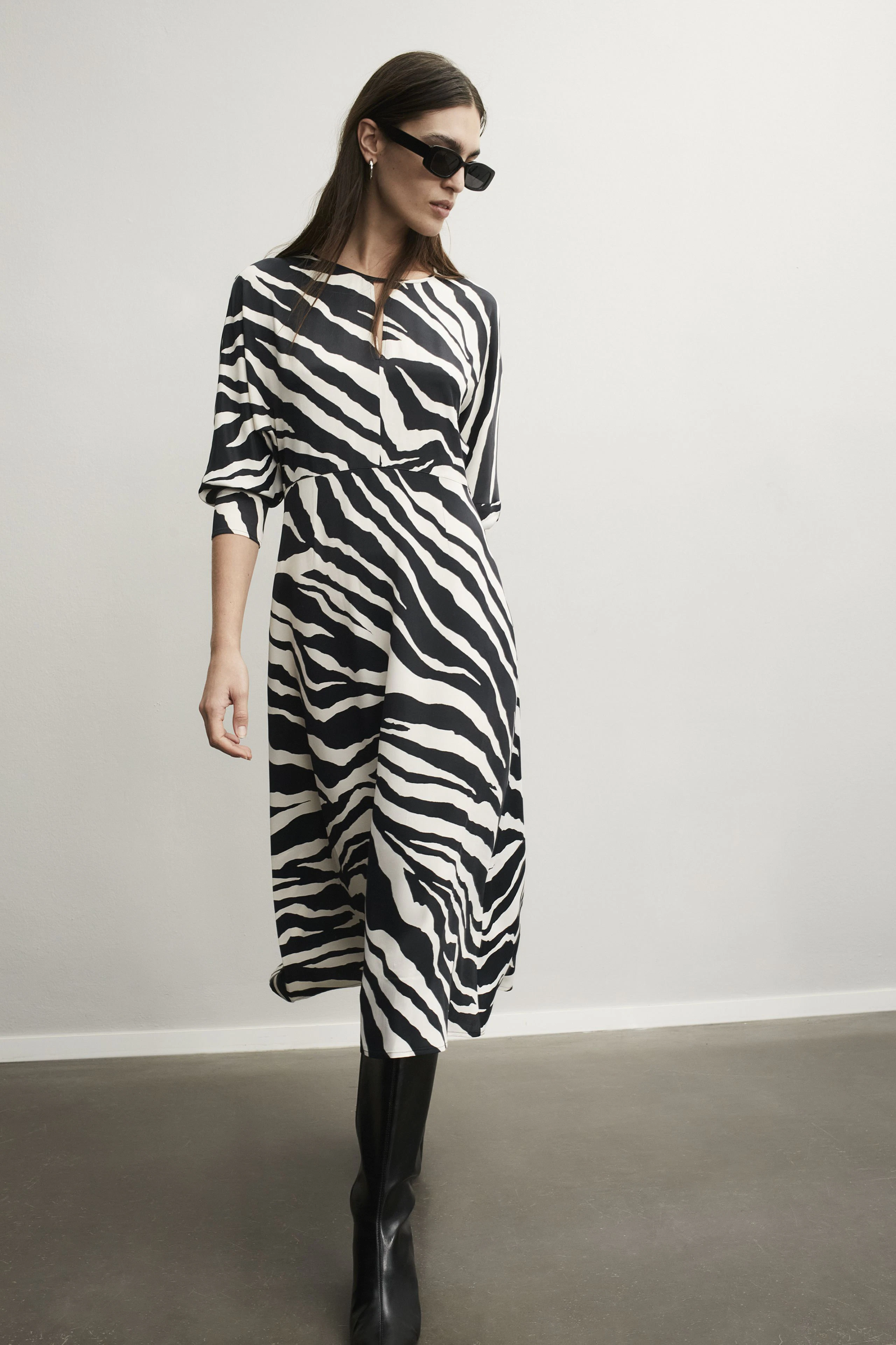 Elegantes Midikleid mit Zebra-Muster: Frau in modischem Kleid und Sonnenbrille steht selbstbewusst.