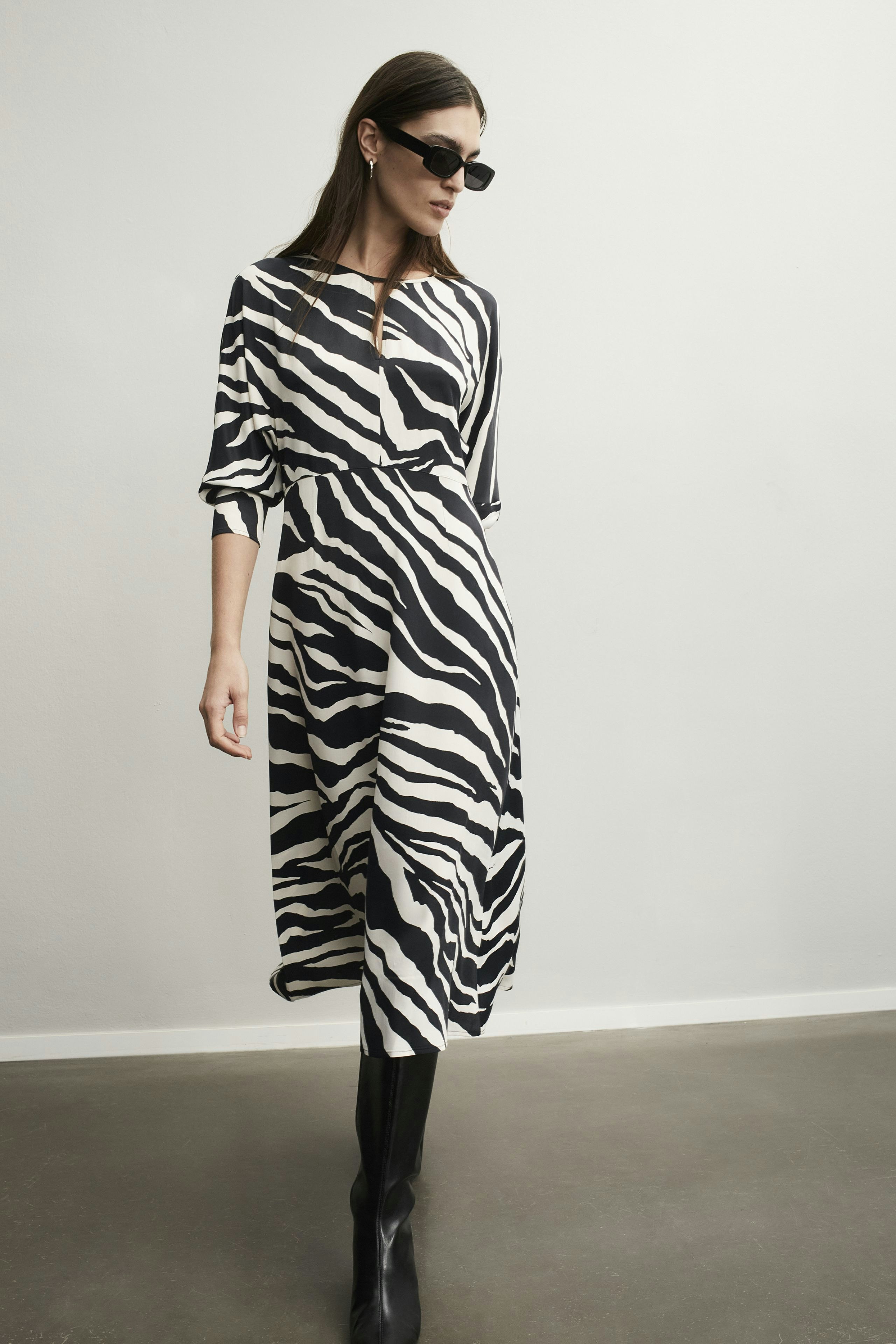 Stylish midi dress: Woman in a black and white zebra print dress, exuding confidence and elegance.