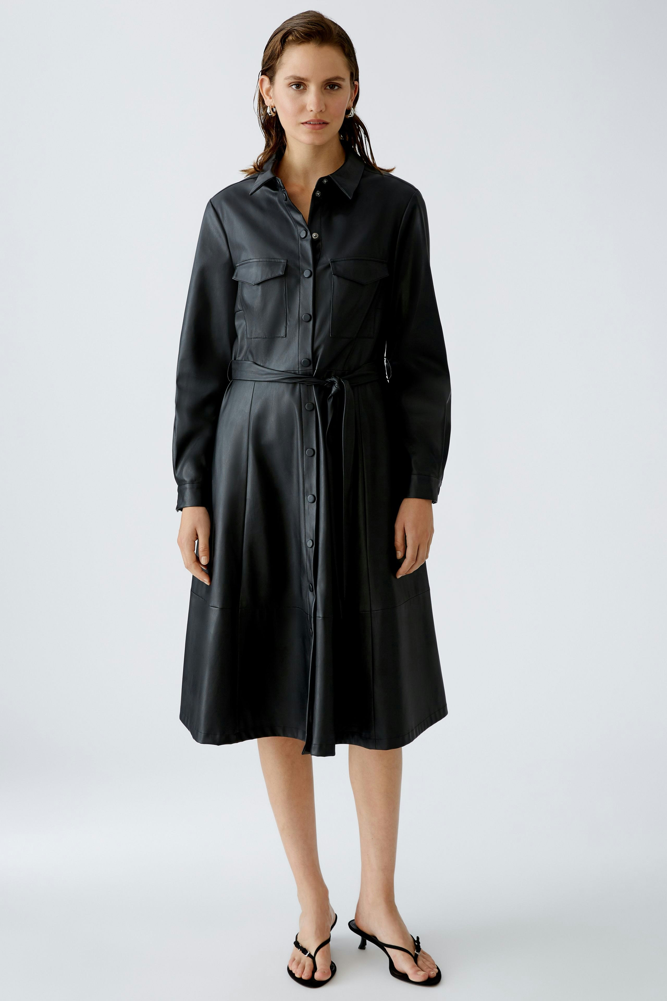 Elegantes Hemdblusenkleid: Frau in schwarzem, knielangem Kleid mit Knopfleiste und Gürtel.