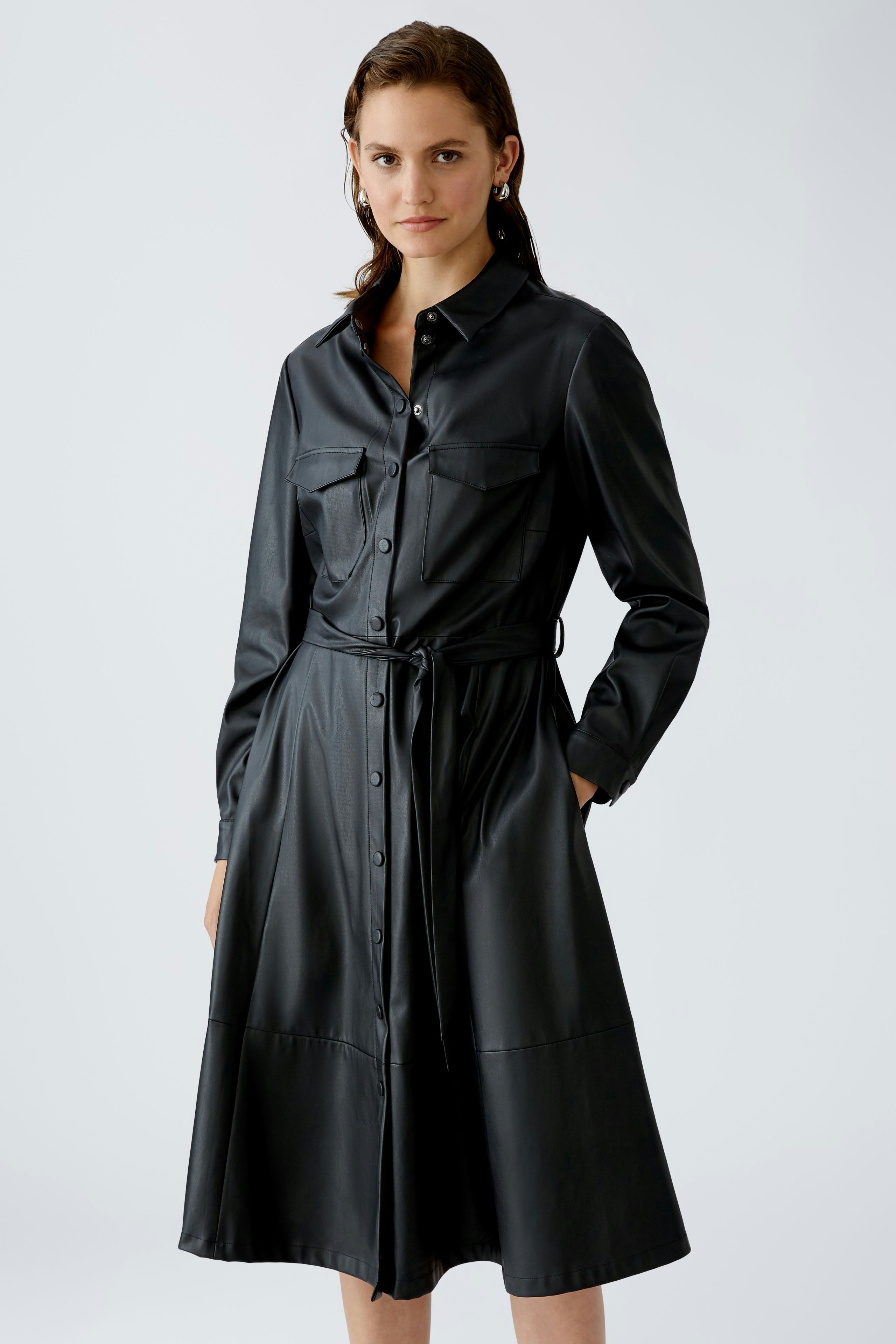 Elegantes Hemdblusenkleid: Frau in schwarzem Kleid mit Knopfleiste und Gürtel, ideal für jeden Anlass.