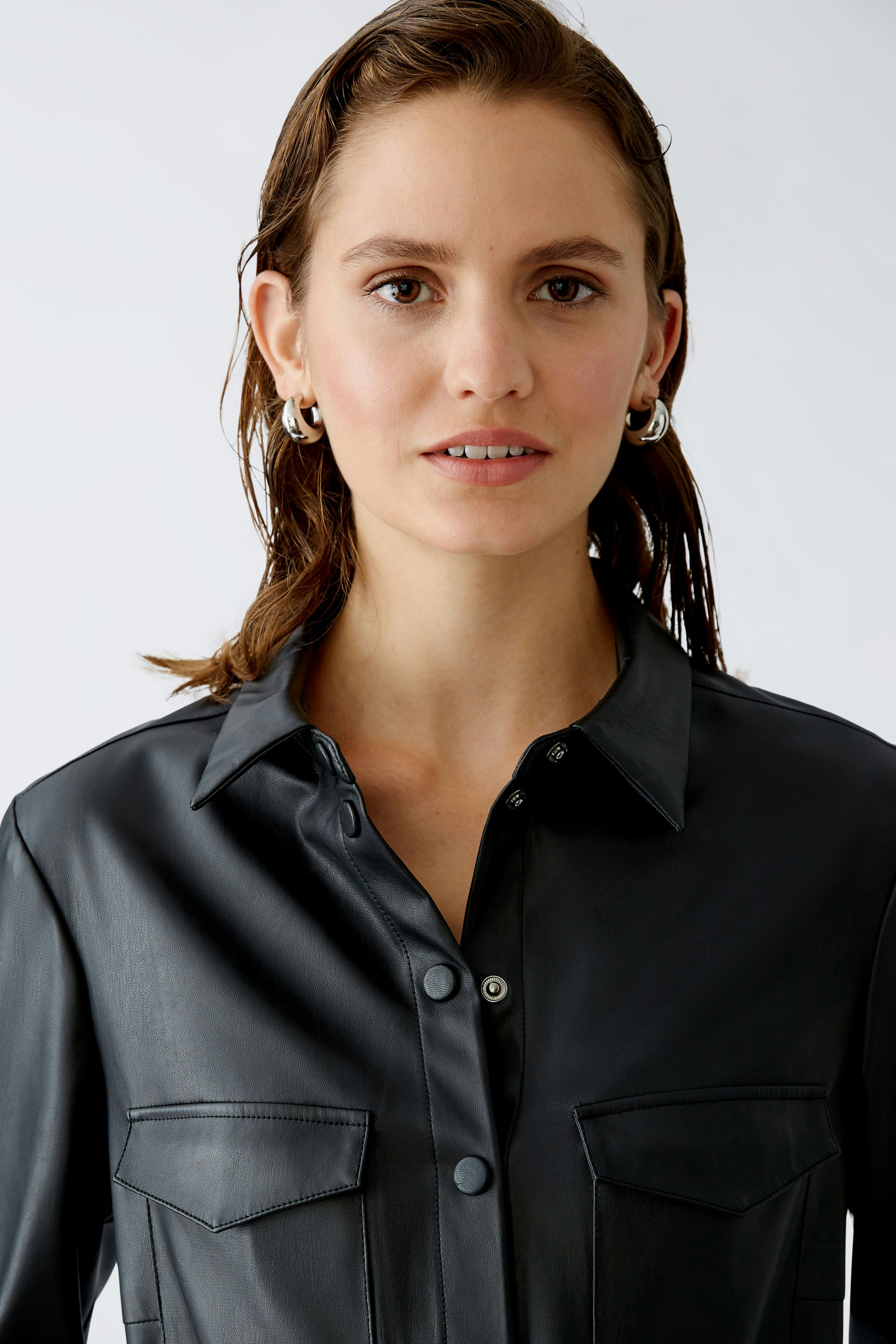 Elegantes Hemdblusenkleid: Frau trägt ein schwarzes, lässiges Hemdblusenkleid mit Taschen.