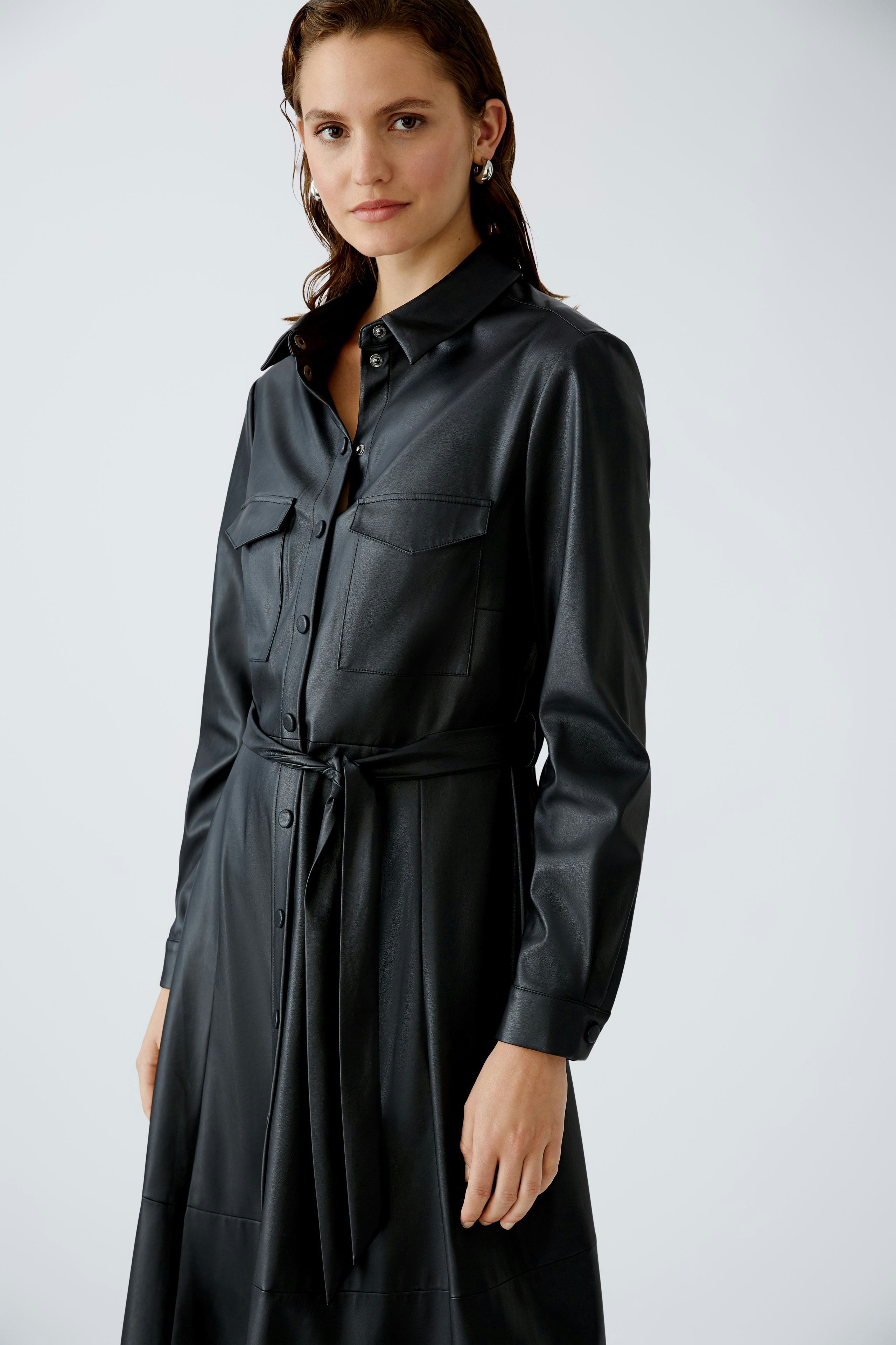 Elegantes Hemdblusenkleid: Frau in schwarzem, tailliertem Kleid mit Knopfleiste und Gürtel.