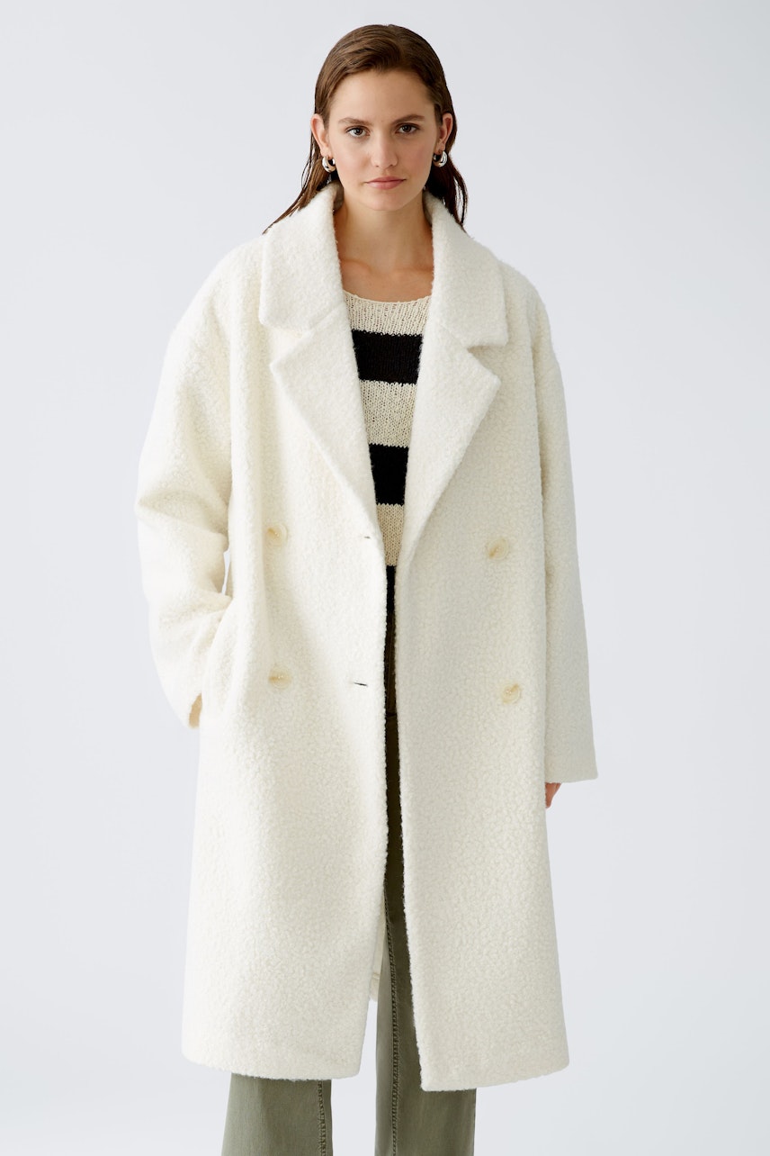 Stylish winter coat: A woman in a cozy white coat over a striped pullover, exuding elegance.