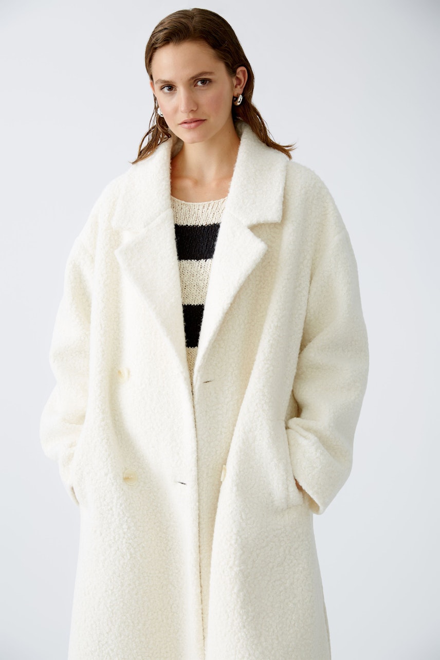 Stylish winter coat: A woman in a cozy white coat over a striped pullover, exuding elegance.