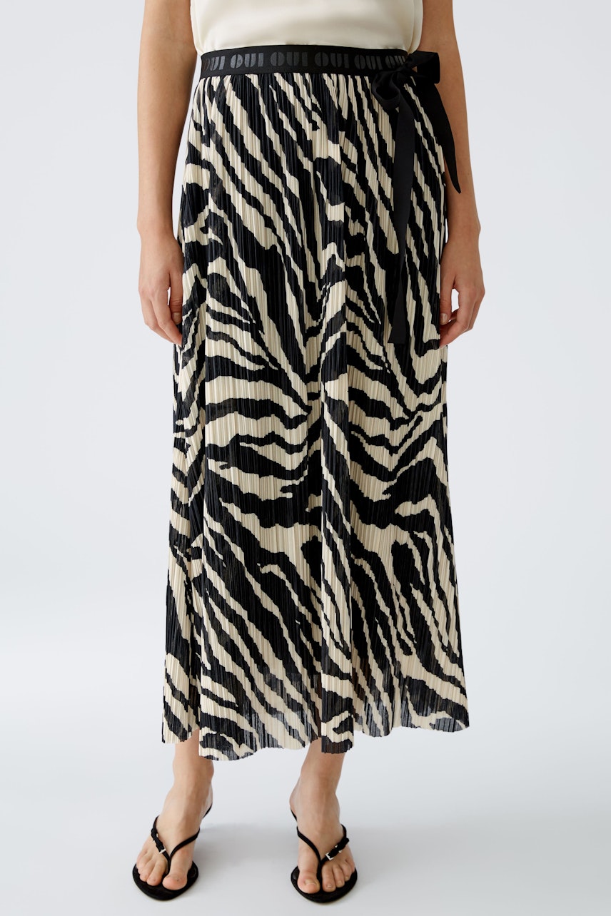 Chic maxi skirt: Woman in a pleated zebra print skirt with a stylish waistband.