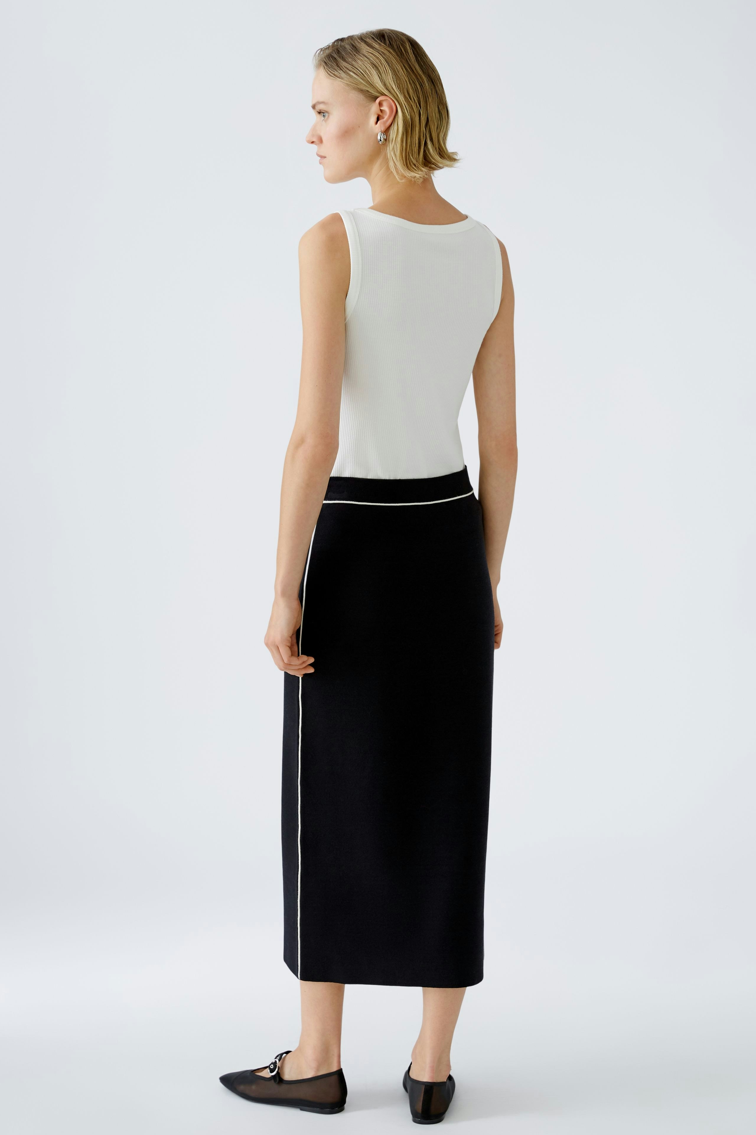 Elegant black knitted skirt: A woman in a sleek, long skirt with a stylish design.