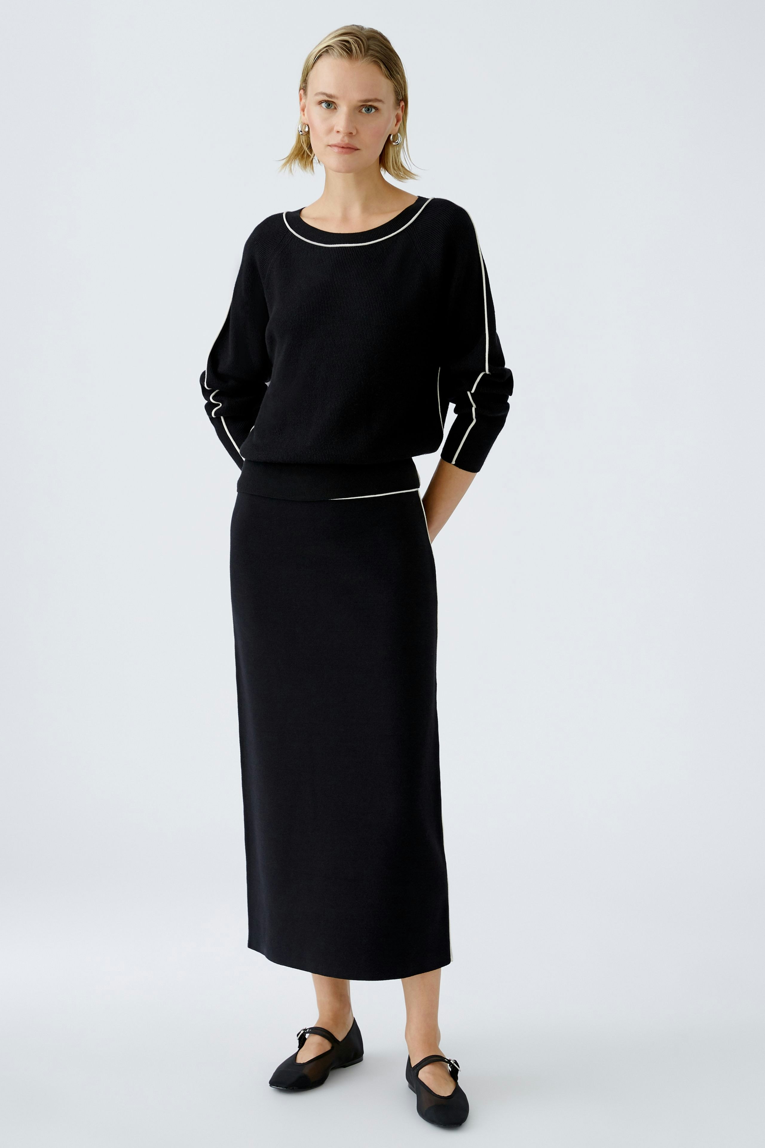 Elegant black knitted skirt: A woman in a fitted black skirt, paired with a stylish pullover.