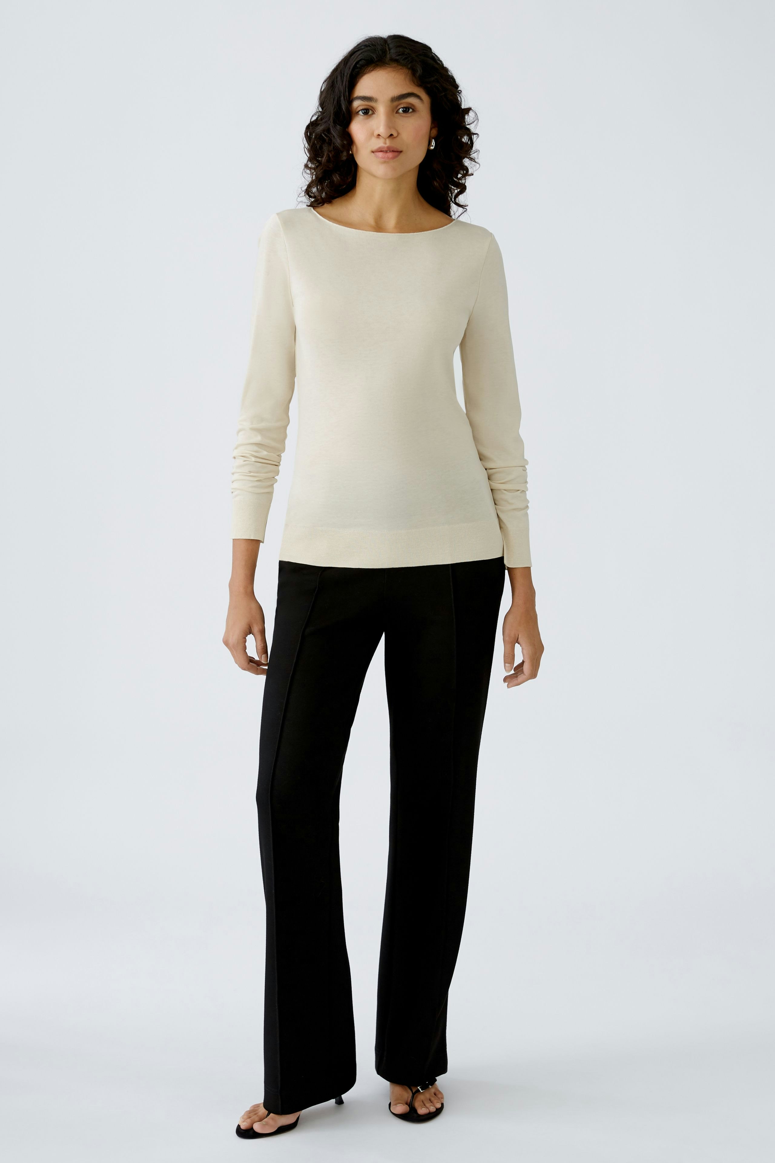 Elegantes Damen-T-Shirt: Frau in cremefarbenem, langärmligem Shirt mit schlichten Details.