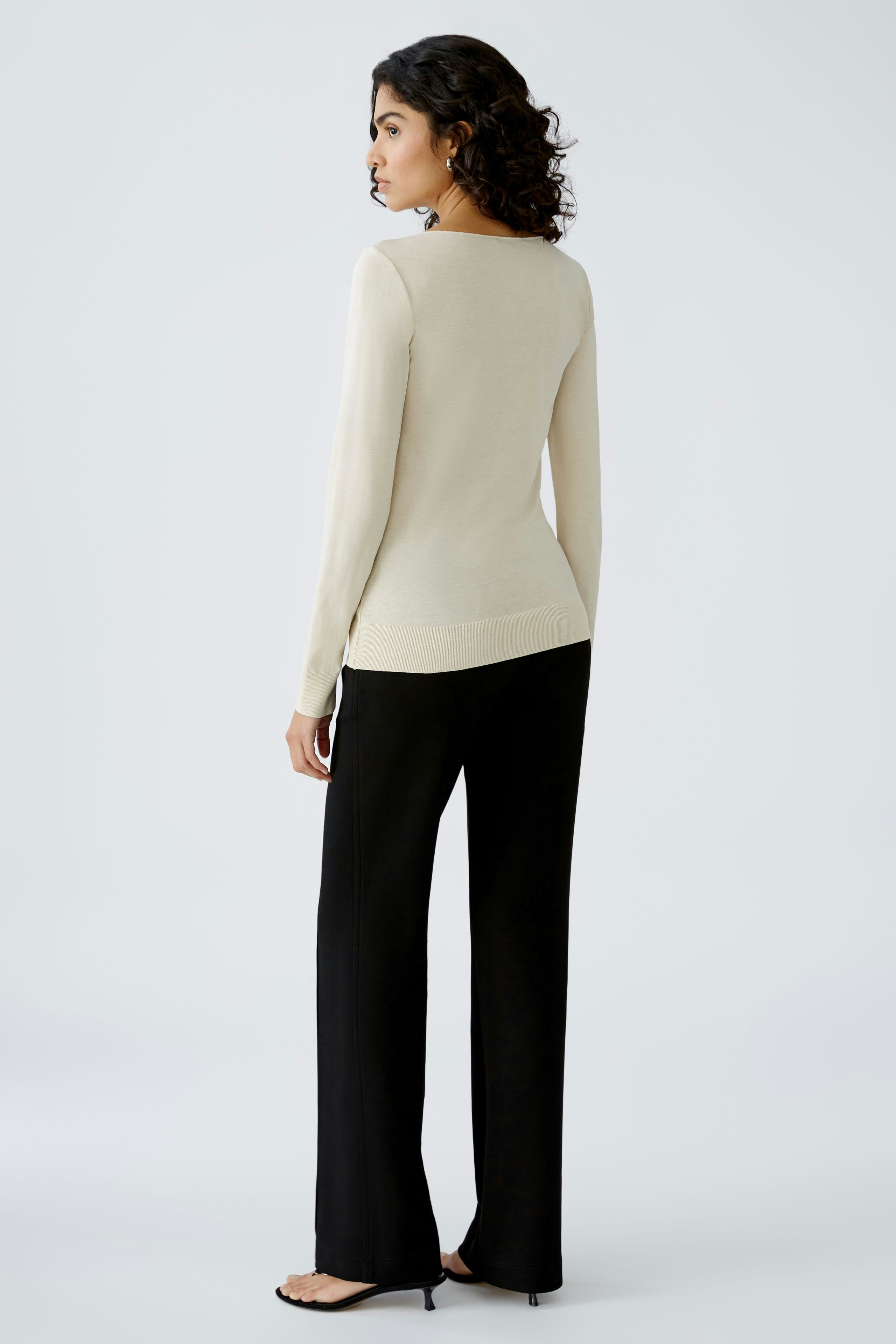 Elegantes Damen-T-Shirt: Frau in beigem T-Shirt mit langen Ärmeln und lässiger Hose.