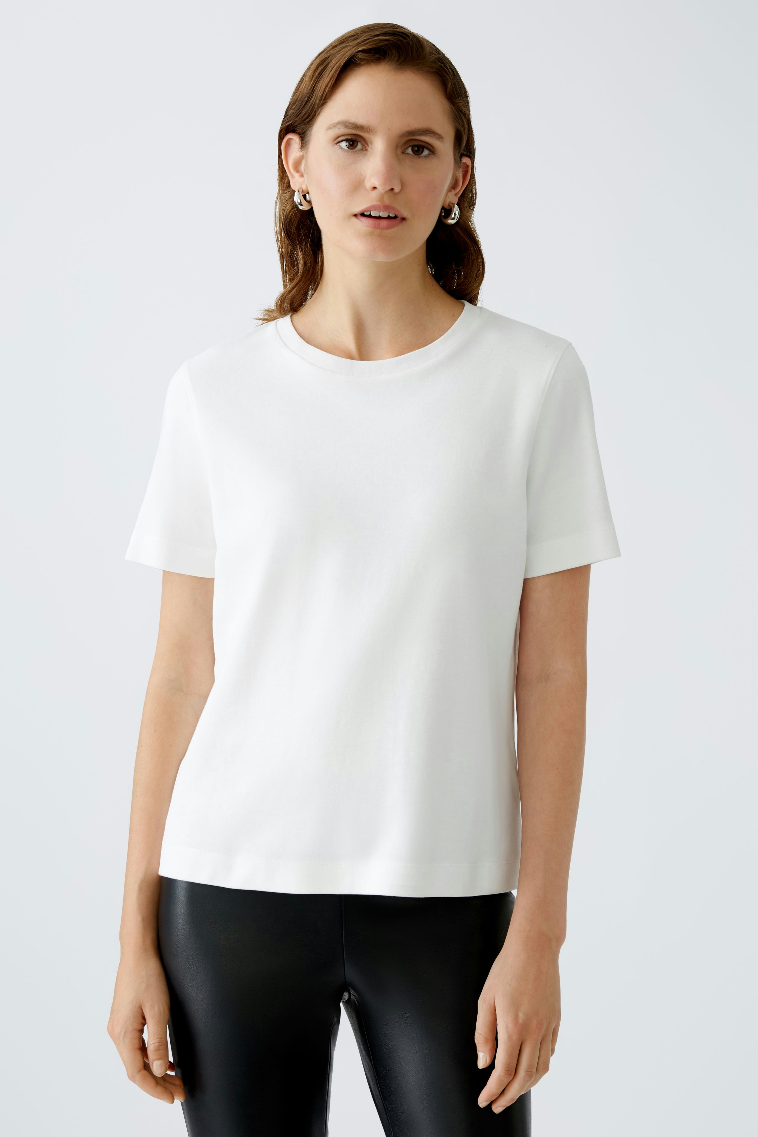 Stylish women's T-shirt: A woman in a white short-sleeve top paired with sleek black pants.
