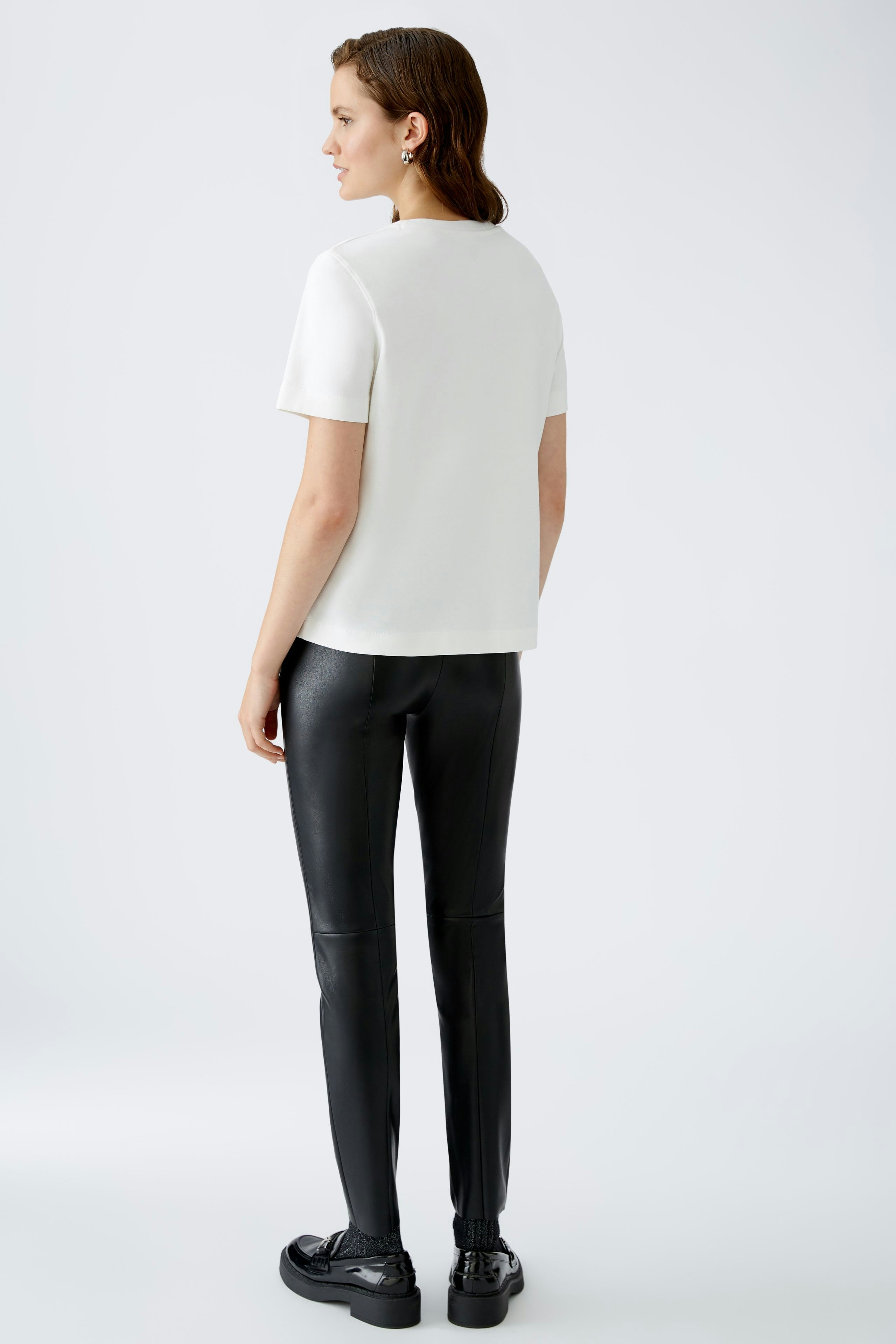 Stylish women's T-shirt: A woman in a white T-shirt paired with sleek black pants.