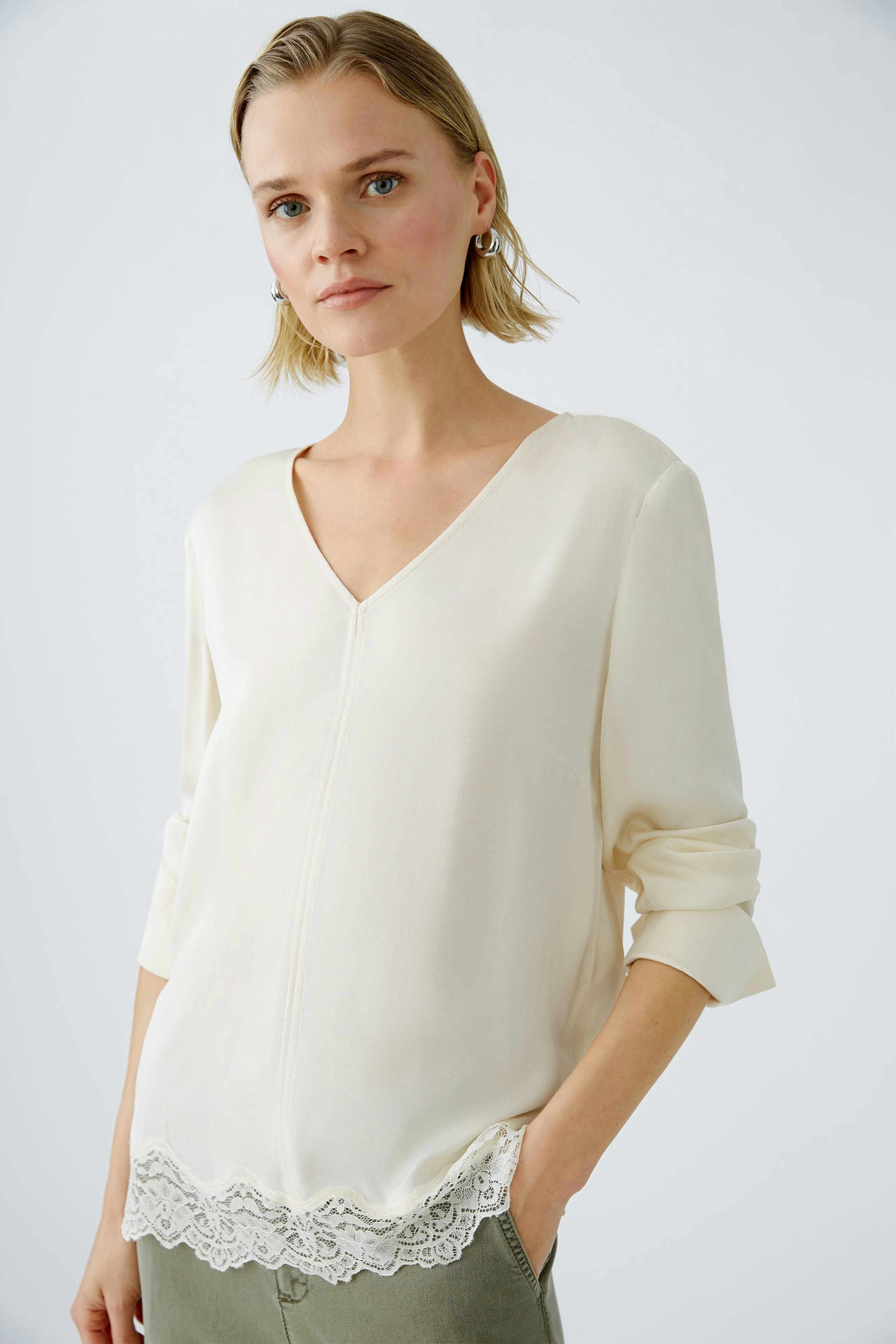 Elegante Damen-Bluse in Creme mit V-Ausschnitt und Spitzenabschluss, ideal für jeden Anlass.