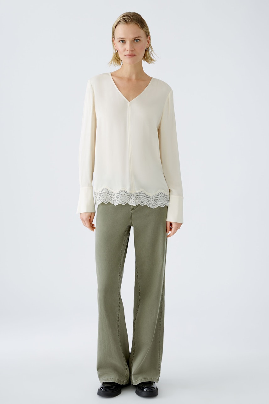 Elegant women's blouse with lace trim, featuring a V-neckline and relaxed fit.