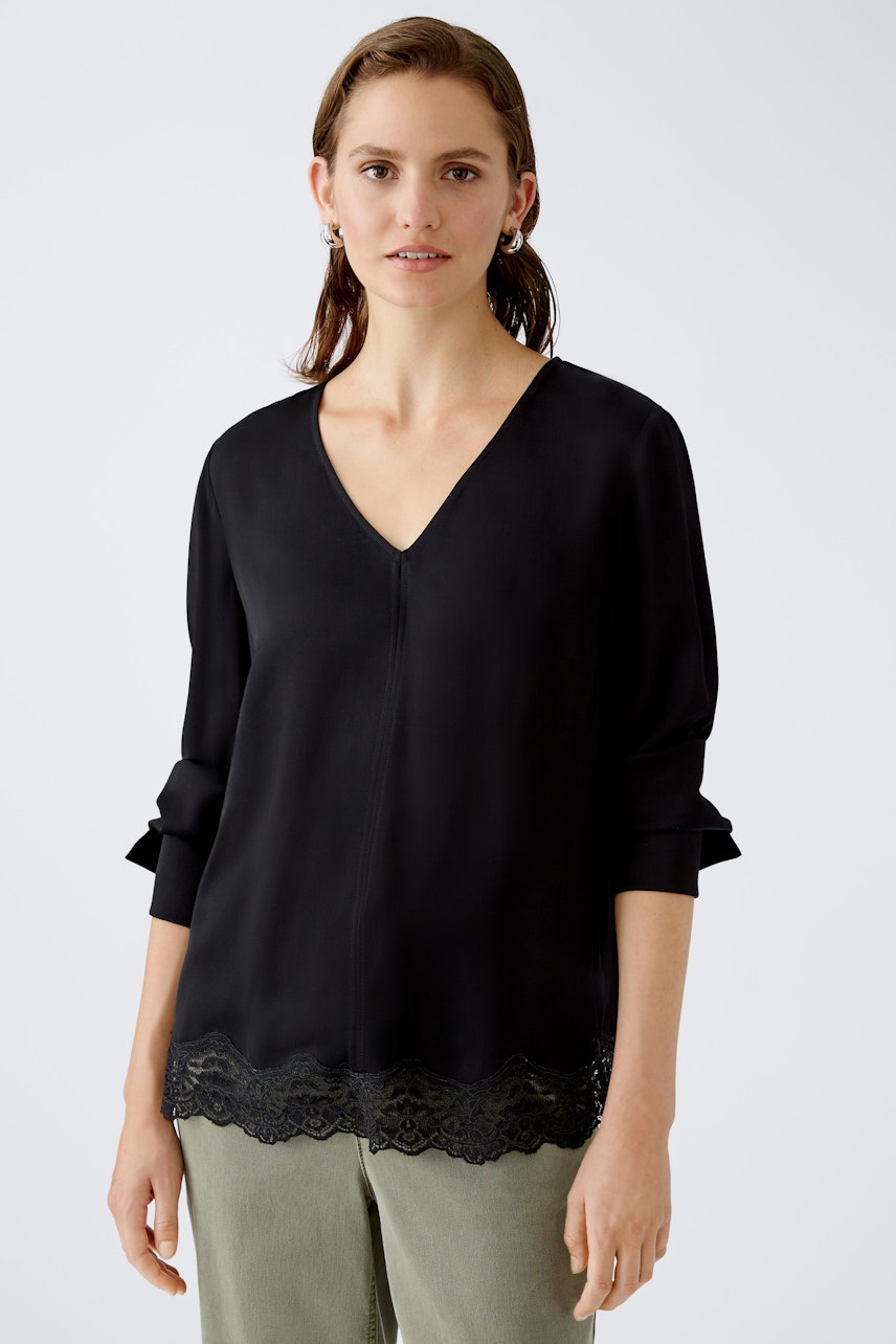 Elegant black blouse with lace trim, worn by a woman, perfect for stylish occasions.