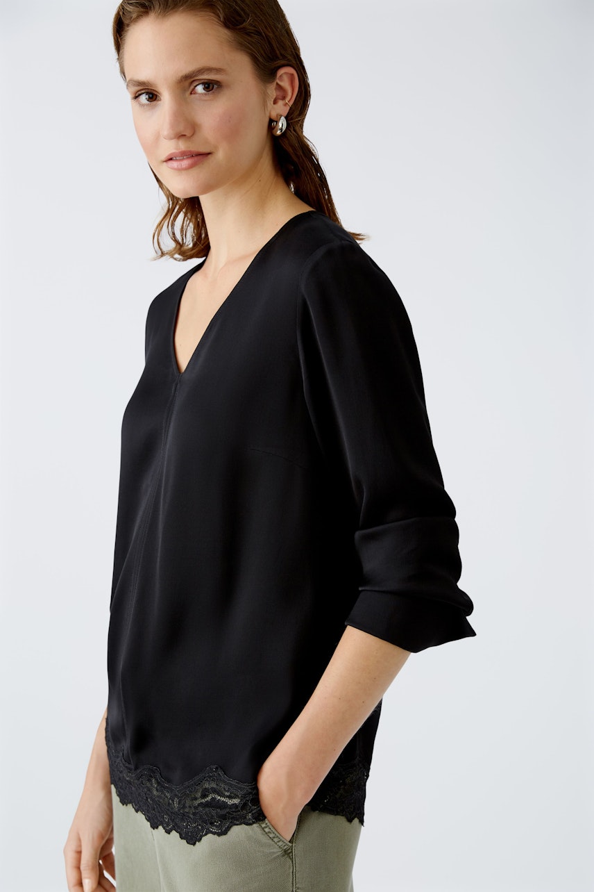 Elegant women's blouse: A woman in a black blouse with lace trim, exuding sophistication and style.