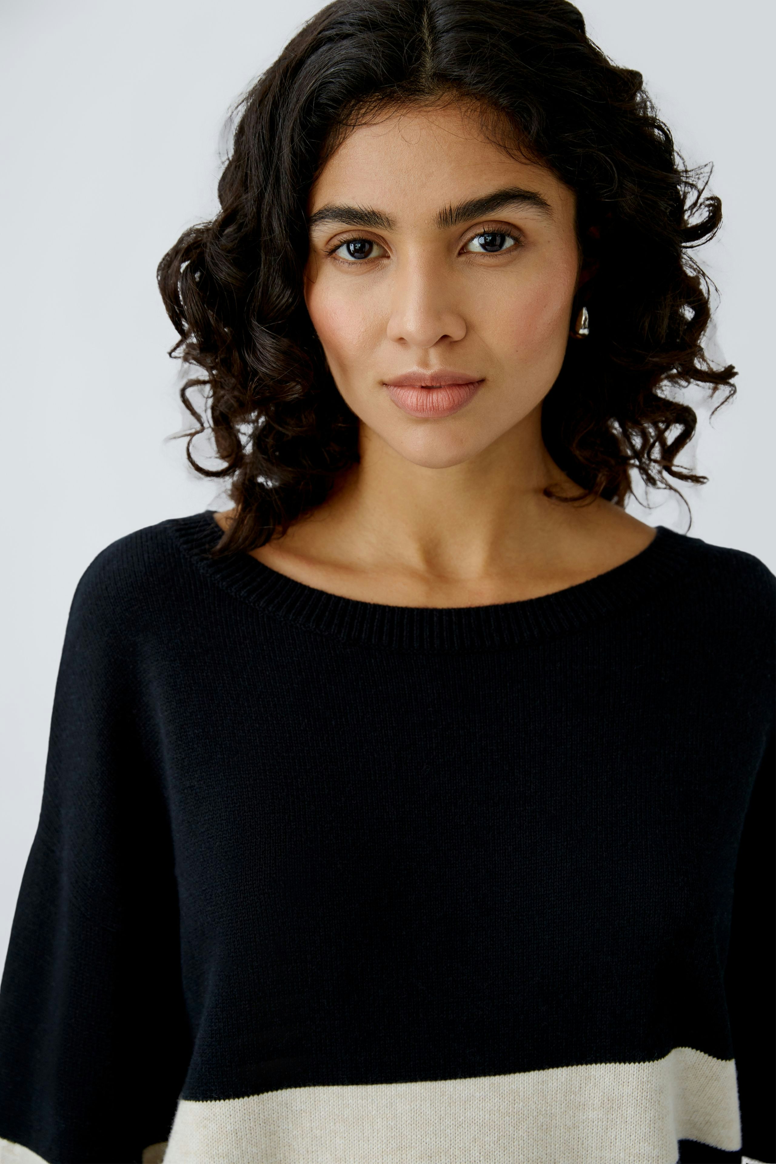 Damen-Pullover: Frau in schwarzem Pullover mit beigem Streifen, lässig und modern.