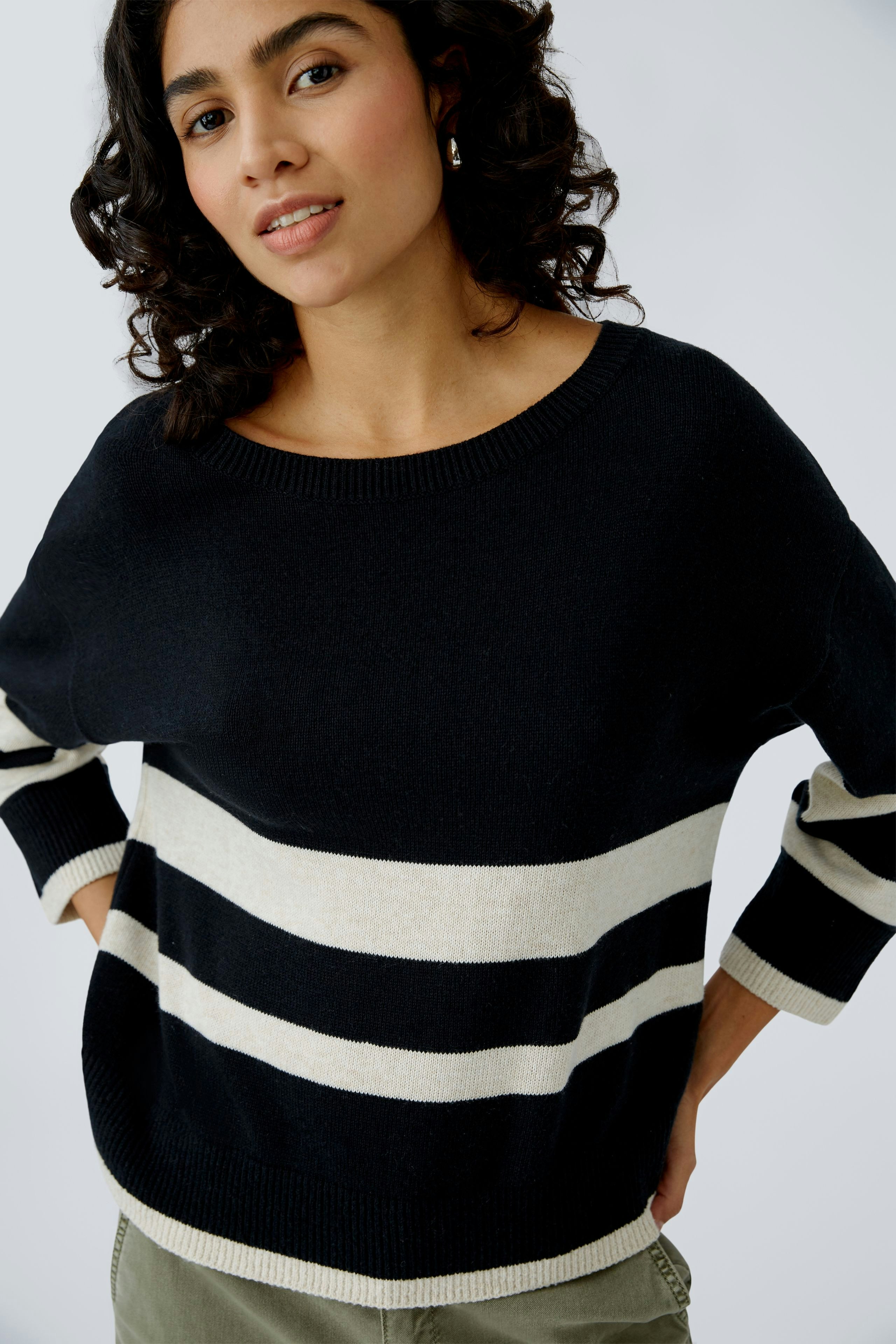 Damen-Pullover: Frau in schwarzem Pullover mit breiten weißen Streifen, lässig und modern.