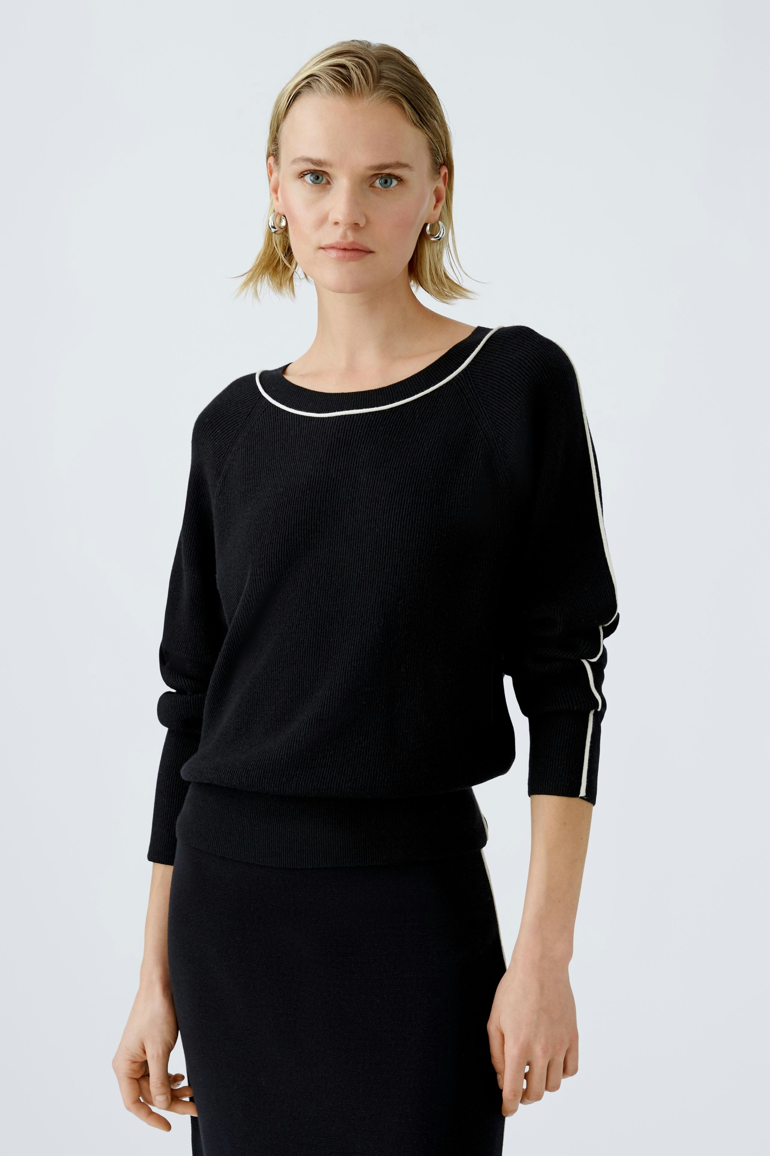 Stylish women's pullover: A woman in a black pullover with white accents, exuding elegance.