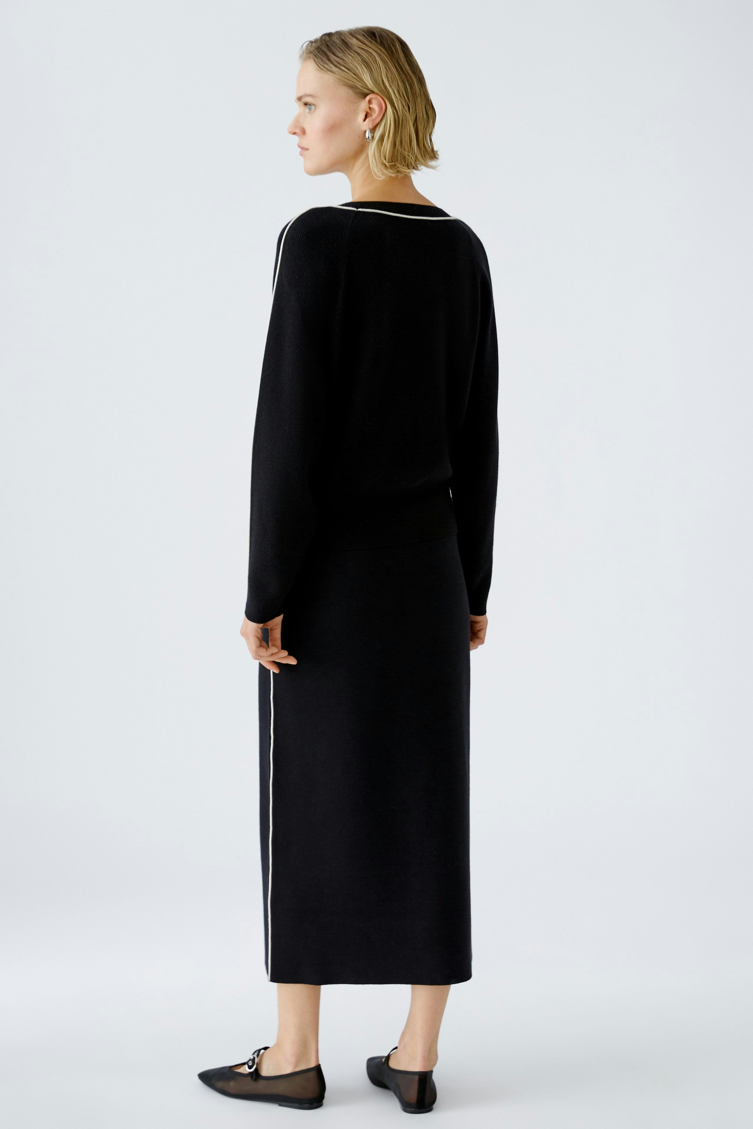 Elegant women's pullover: A woman in a black pullover with a sleek design, showcasing a modern silhouette.