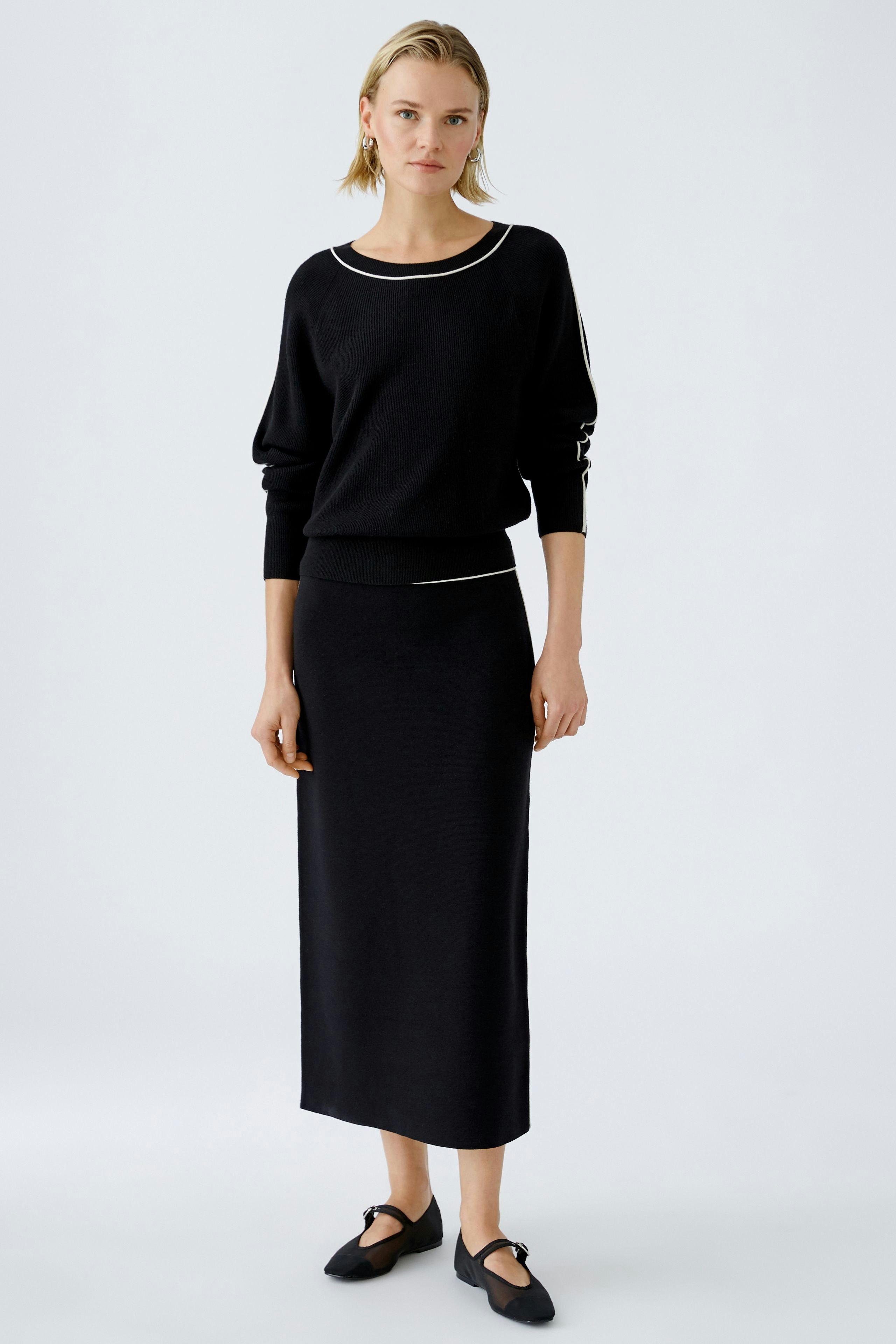 Elegant women's pullover: A woman in a black pullover paired with a matching skirt, exuding sophistication.