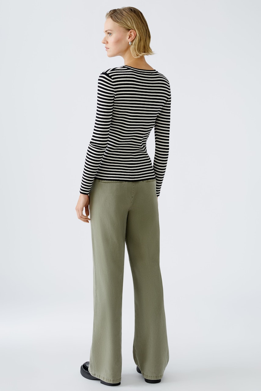 Stylish women's pullover: A woman in a striped pullover and relaxed pants, showcasing a modern look.