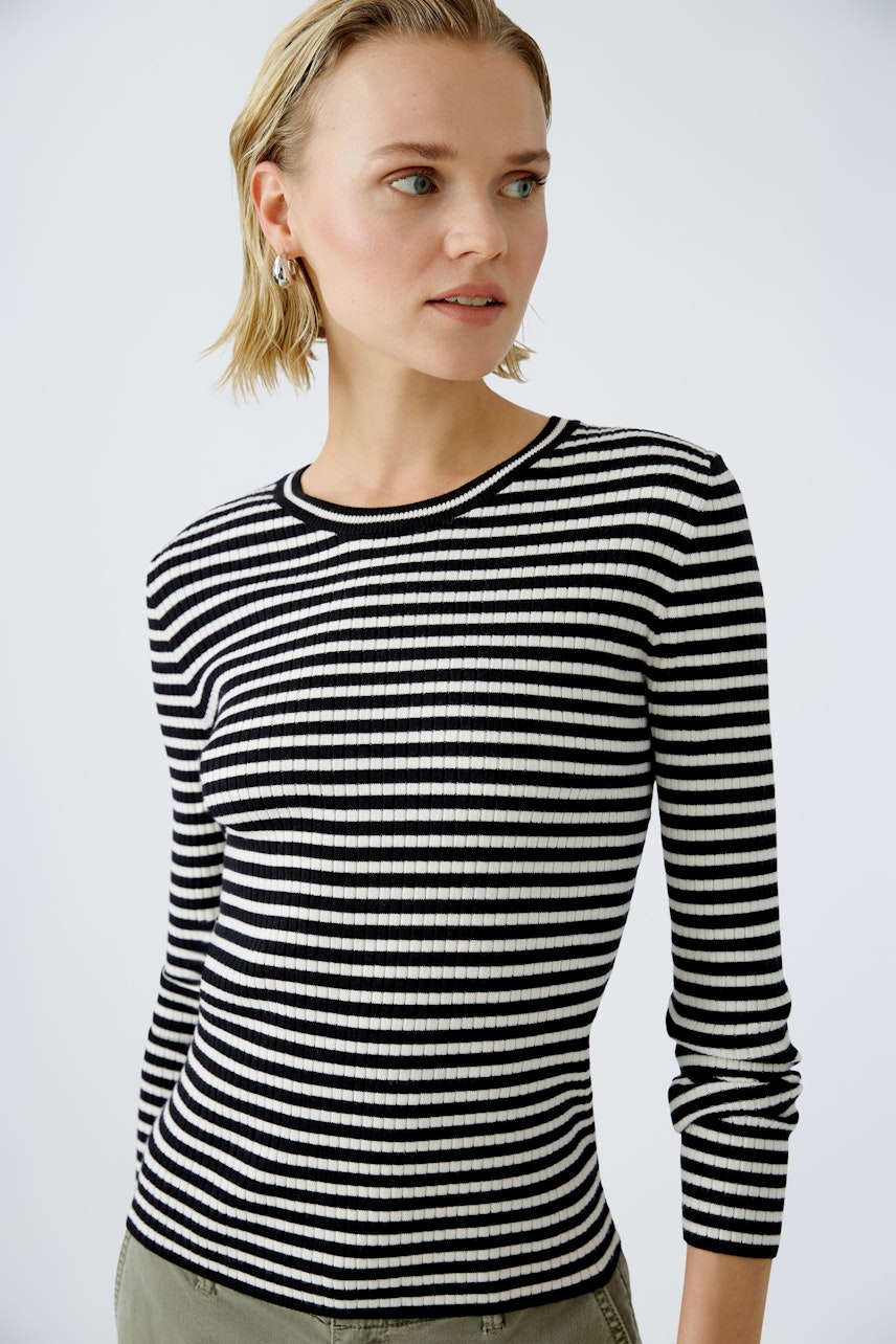 Stylish women's pullover: A woman in a black and white striped ribbed pullover, exuding casual elegance.