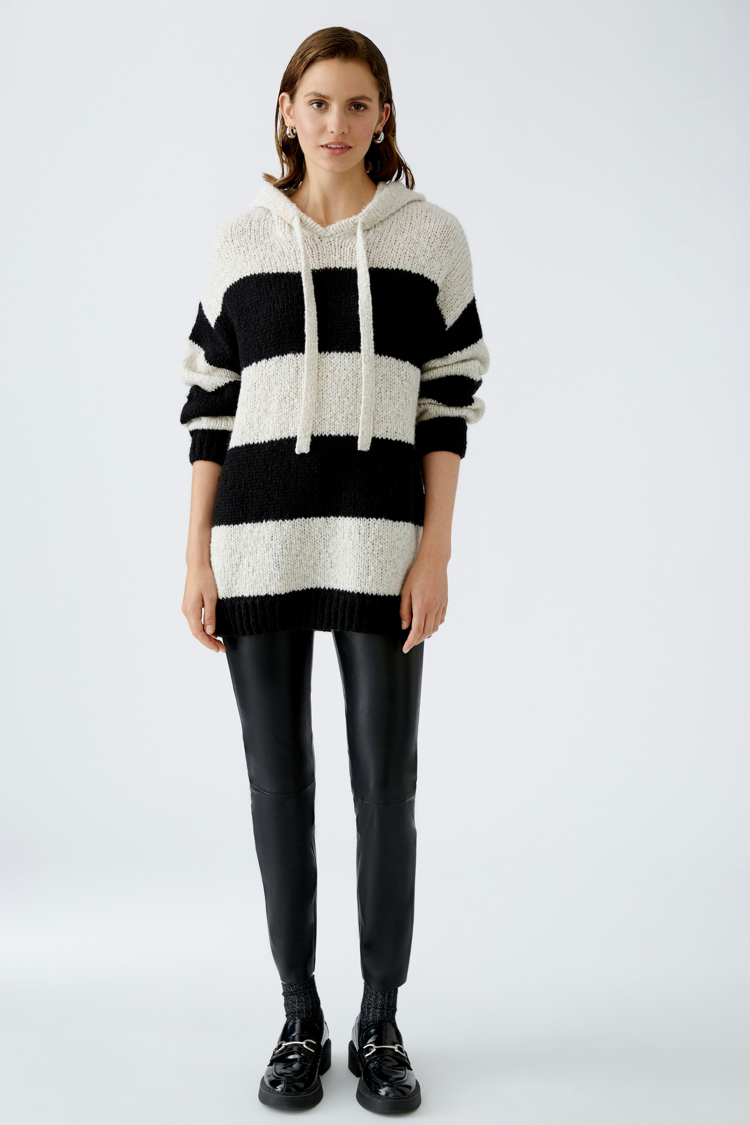 Stylish women's hoodie: A woman in a black and white striped pullover with a relaxed fit.
